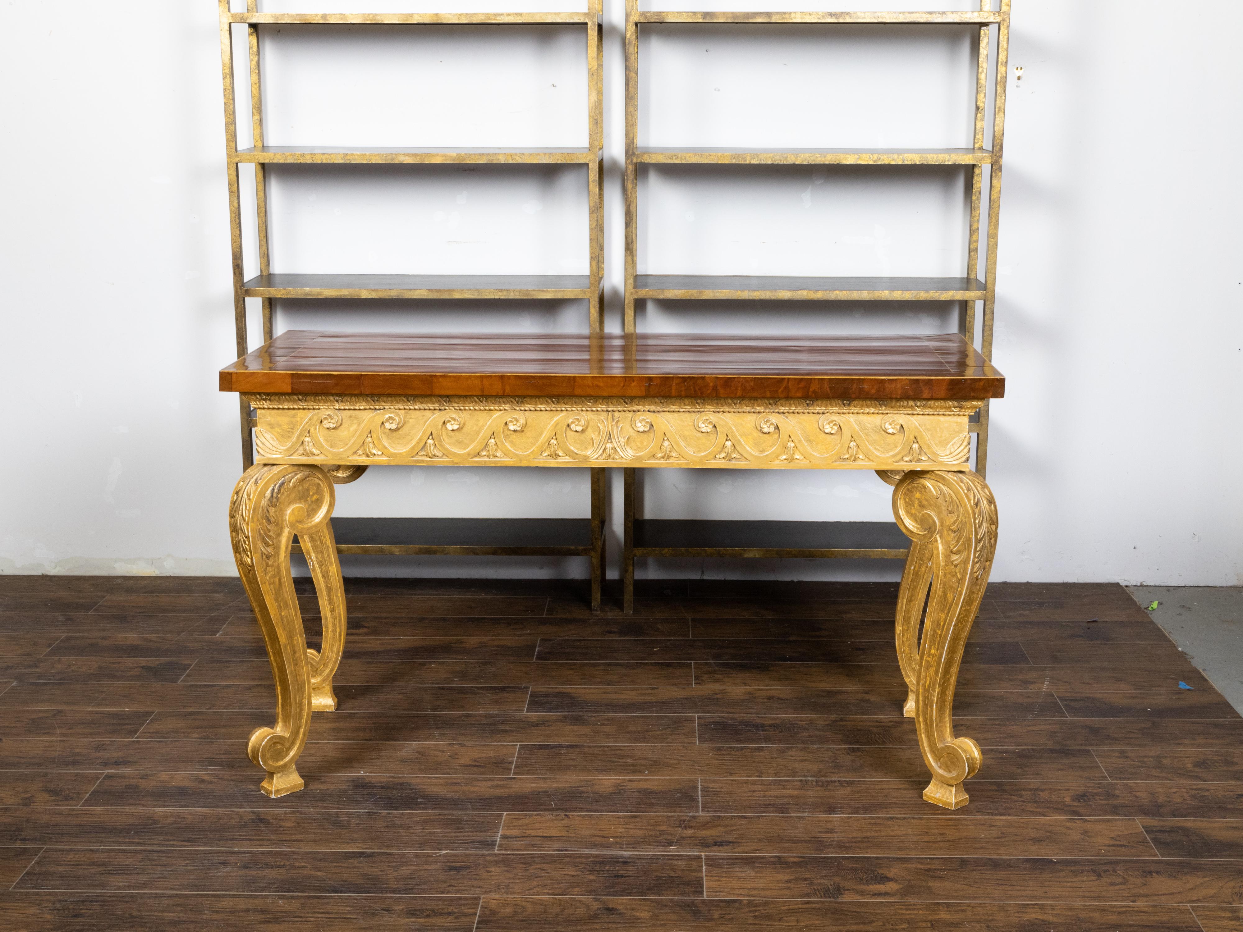 An English giltwood console table from the early 19th century with mahogany veneered top, brass banding, Vitruvian scroll motifs, cabriole legs and acanthus leaves. Created in England during the early years of the 19th century, this console table