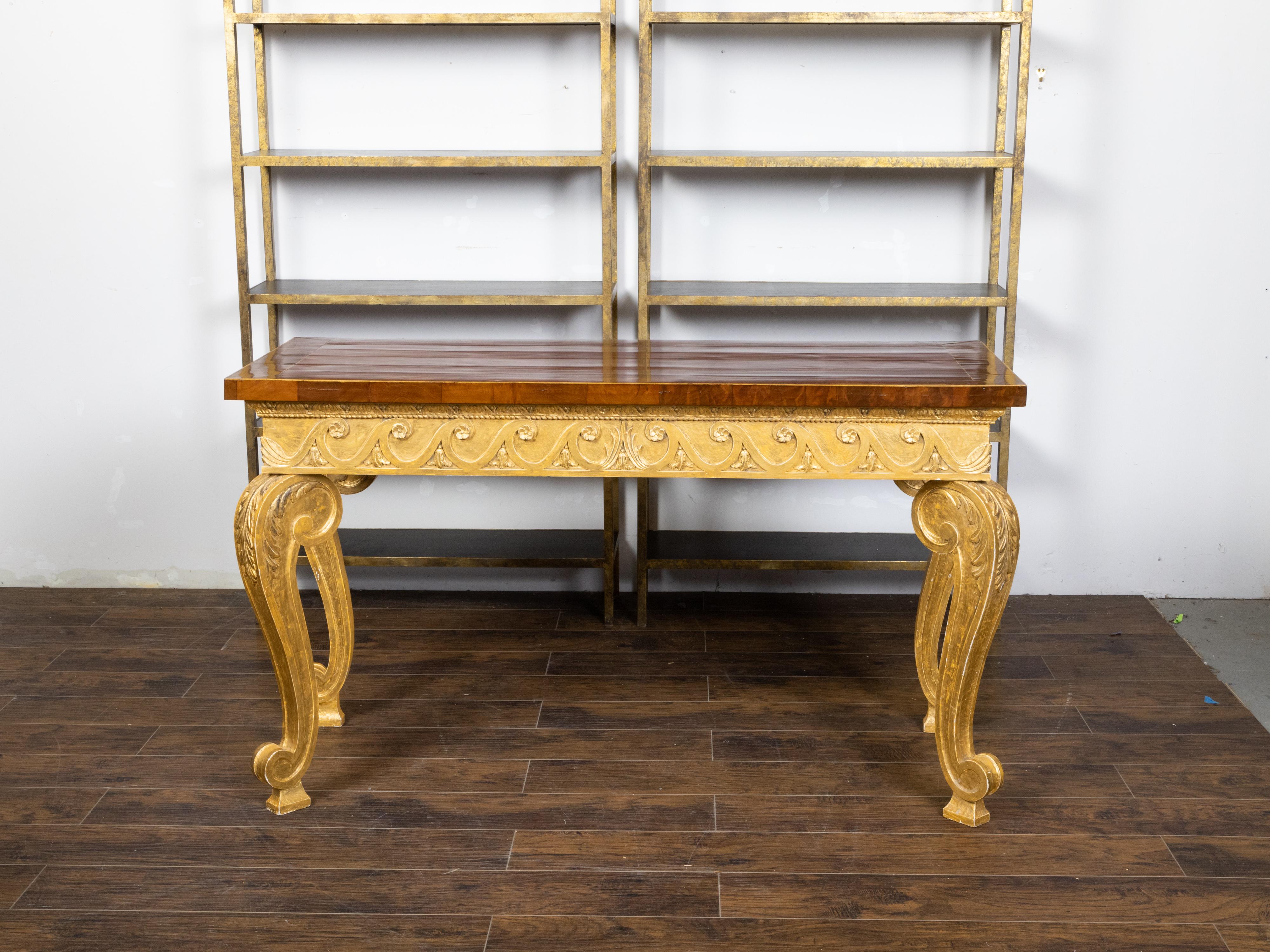 An English giltwood console table from the early 19th century with mahogany veneered top, brass banding, Vitruvian scroll motifs, cabriole legs and acanthus leaves. Created in England during the early years of the 19th century, this console table