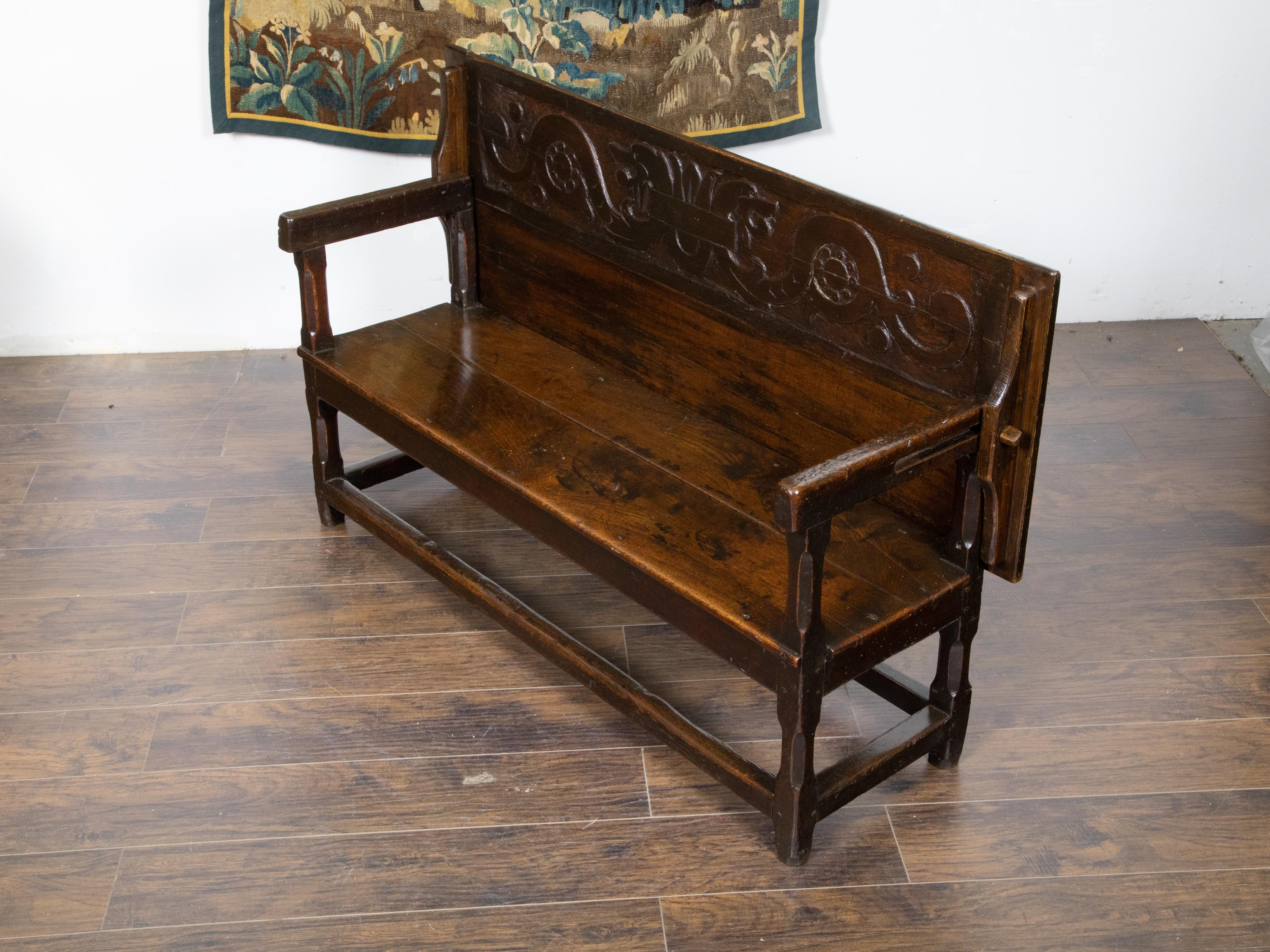 An English George III period metamorphic oak bench from the early 19th century, with carved scrollwork and transforming into a table with lower shelf. Created in the early years of the 19th century during the reign of King George III, this oak piece