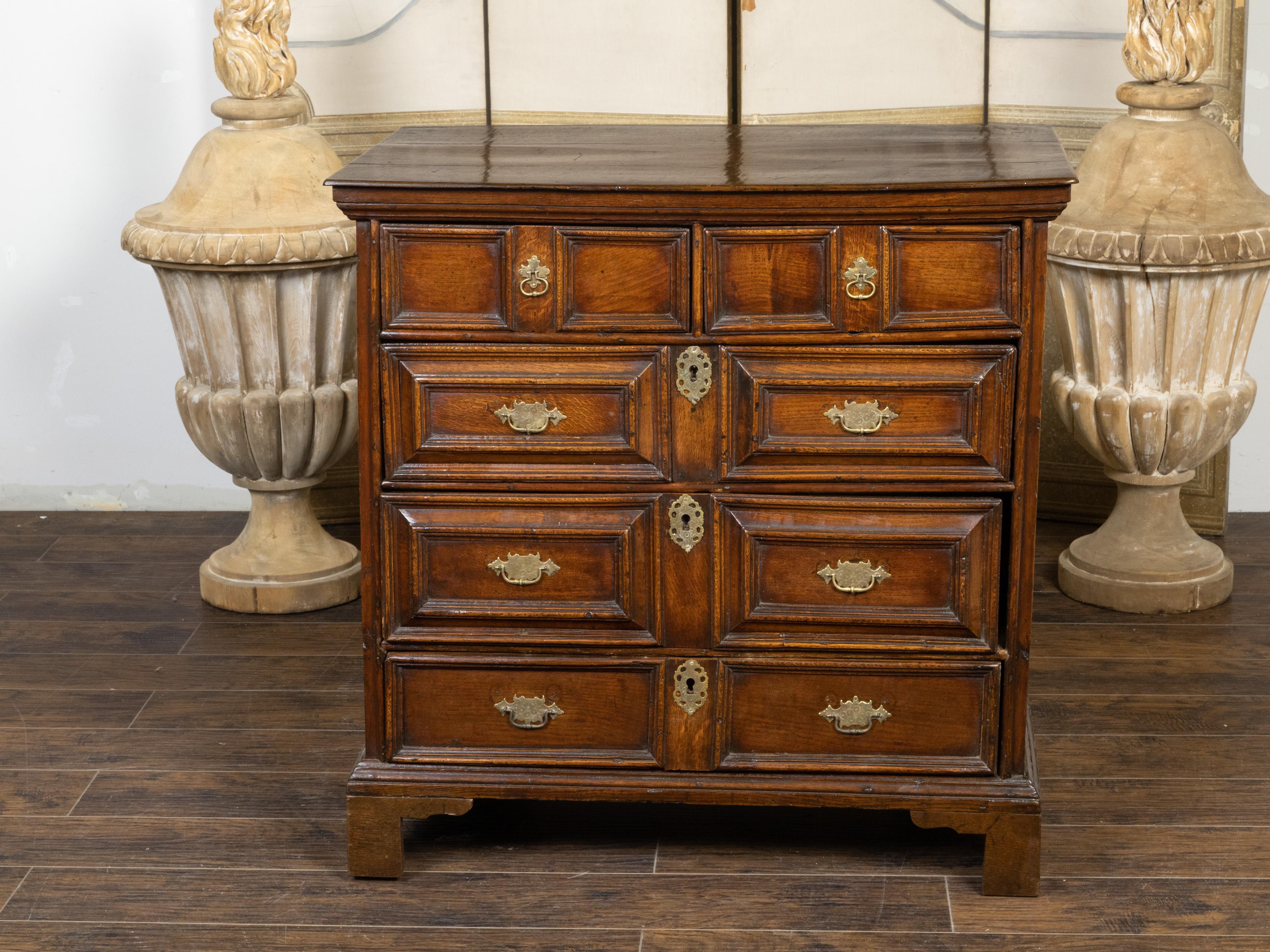 An English George III period oak geometric front chest from the early 19th century, with five drawers, brass Chippendale style hardware and bracket feet. Created in England during the first quarter of the 19th century, this George III period oak
