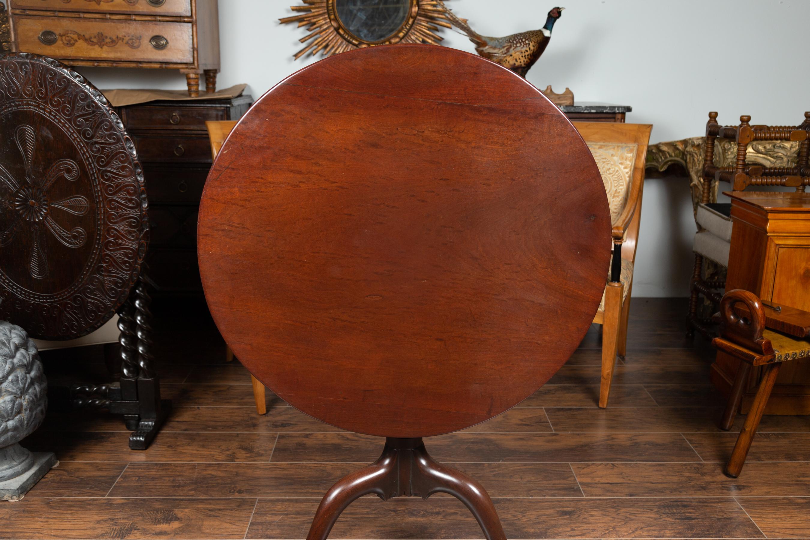 An English Georgian period mahogany tilt-top table from the early 19th century, with pedestal tripod base. Born in England during the later years of King George III's reign, this charming mahogany table features a circular tilt-top resting on a