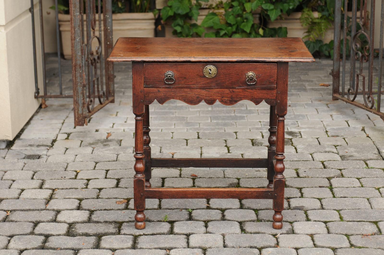 An English Georgian period oak side table from the early 19th century, with single drawer, turned baluster legs and side stretcher. Born during the first quarter of the 19th century, this charming Georgian table features a rectangular planked top