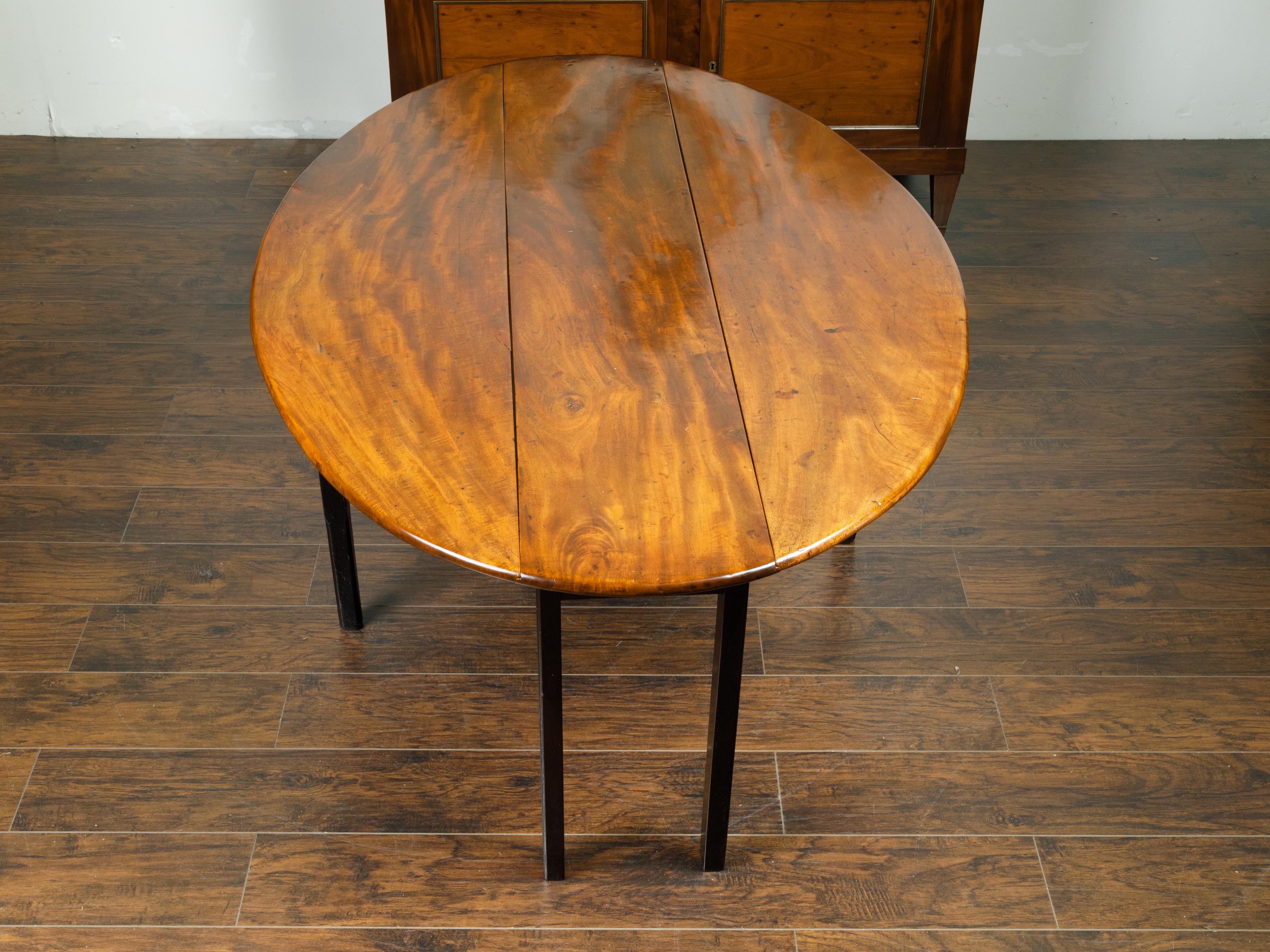 19th Century English 1820s Mahogany Drop Leaf Dining Table with Oval Top and Ebonized Legs
