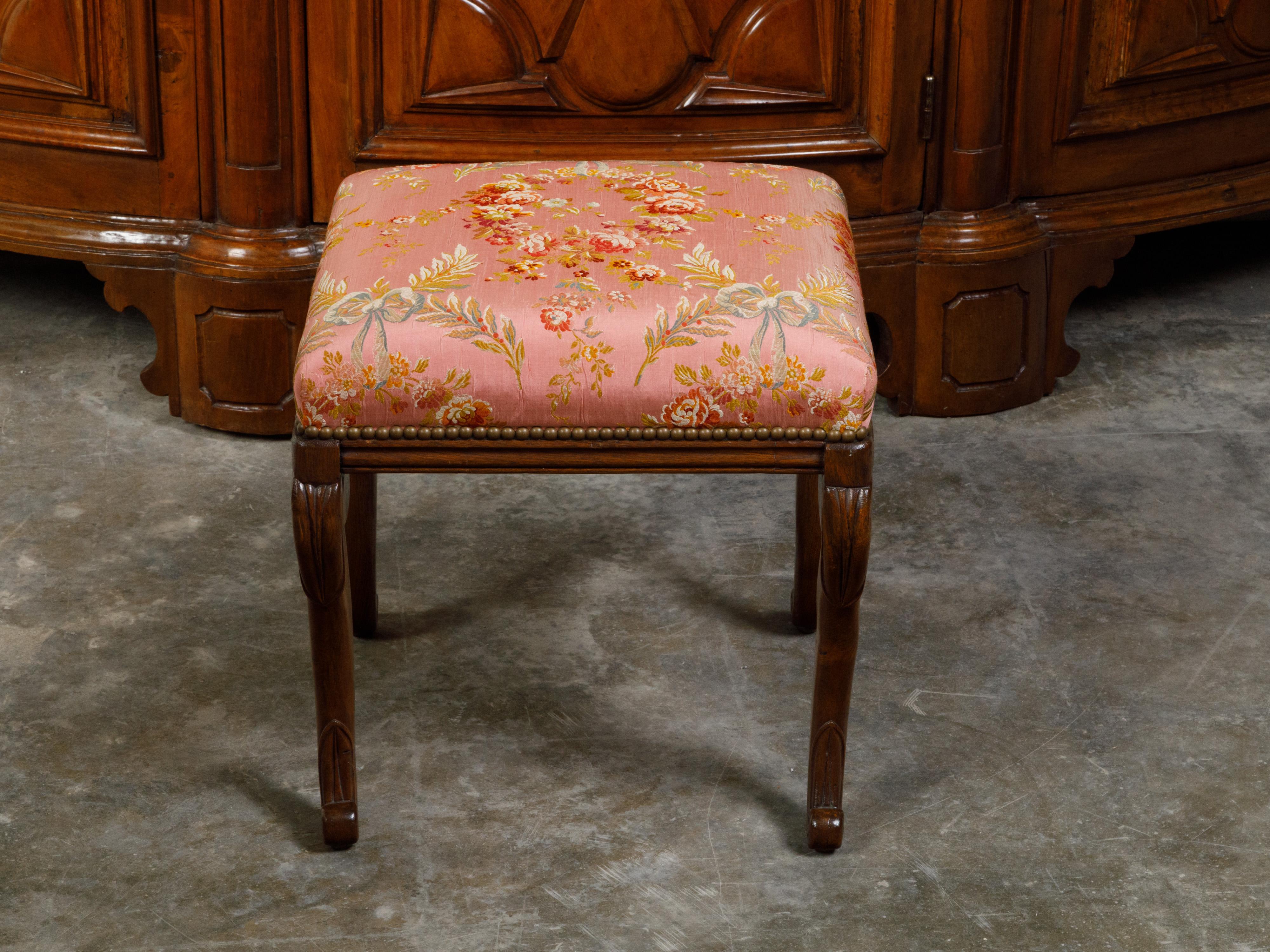 An English Regency period mahogany stool from the early 19th century, with cabriole legs and floral upholstery. Created in England during the first quarter of the 19th century, this mahogany stool attracts our attention with its square pink