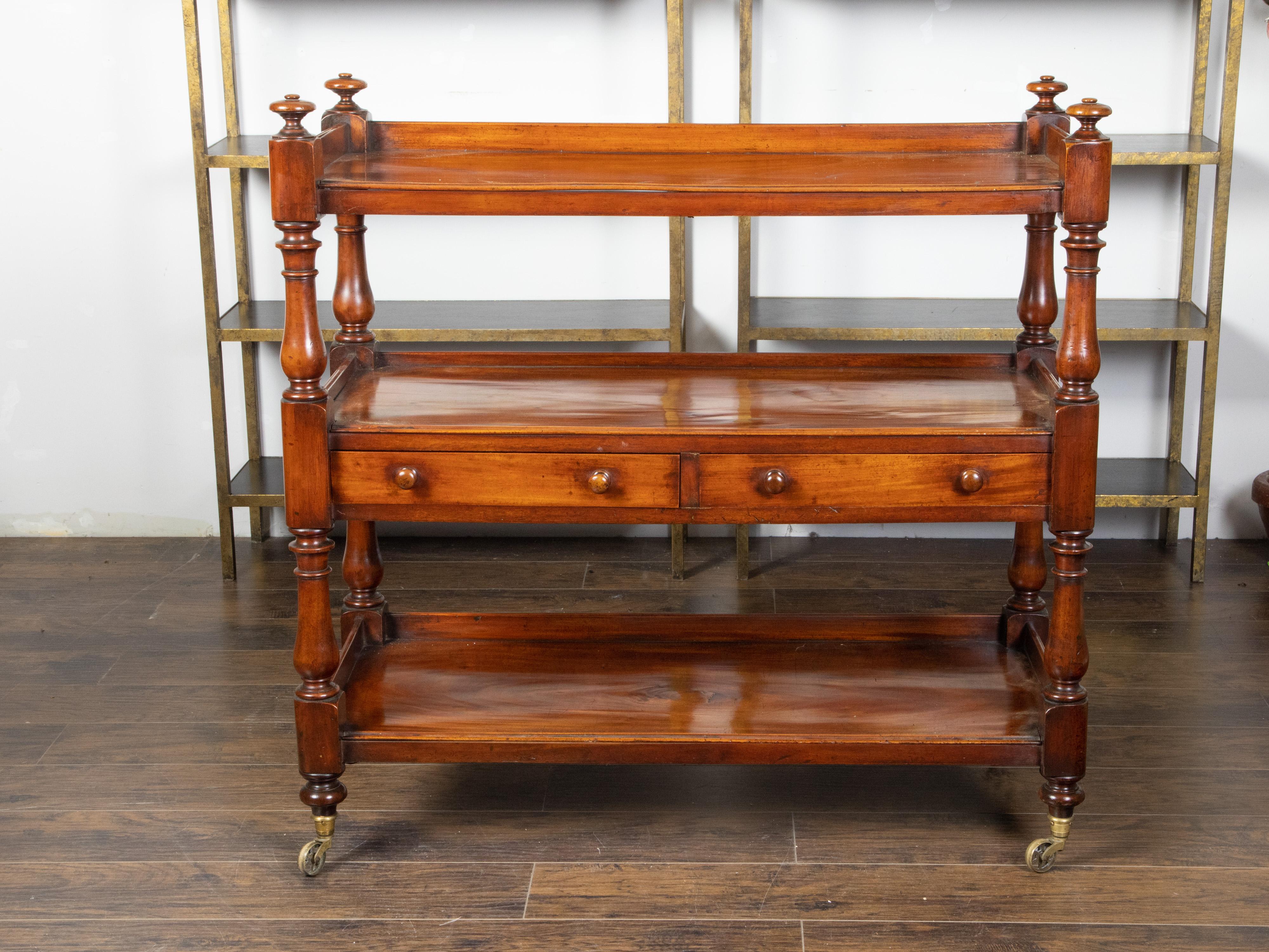 An English mahogany trolley from the early 19th century, with two drawers and brass casters. Created in England during the first quarter of the 19th century, this mahogany trolley features an upper shelf surrounded by a three-quarter gallery