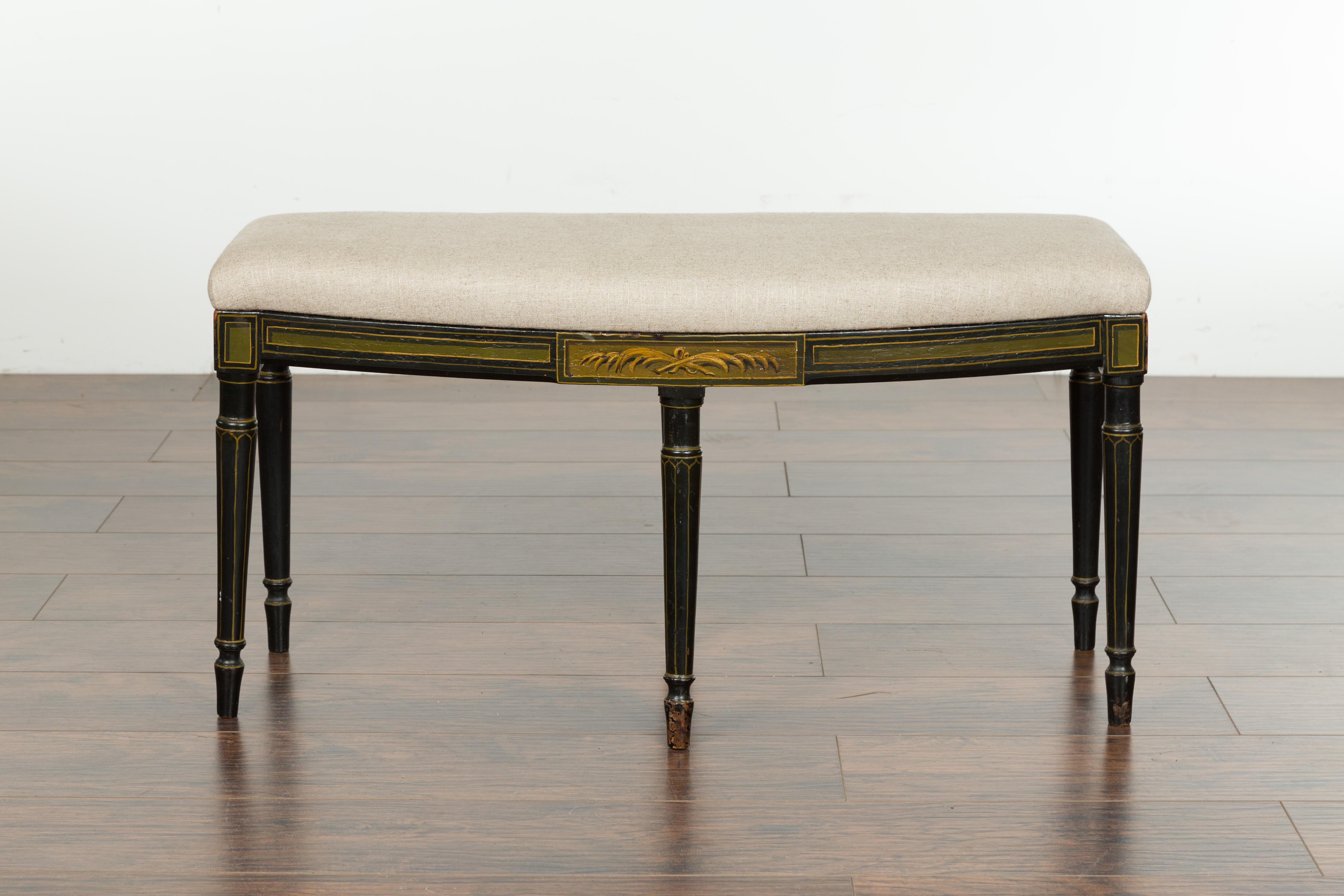 An English Regency period small black bench from the early 19th century, with painted foliage, column legs and new upholstery. Created in England during the first quarter of the 19th century, this Regency bench features a rectangular seat with bow