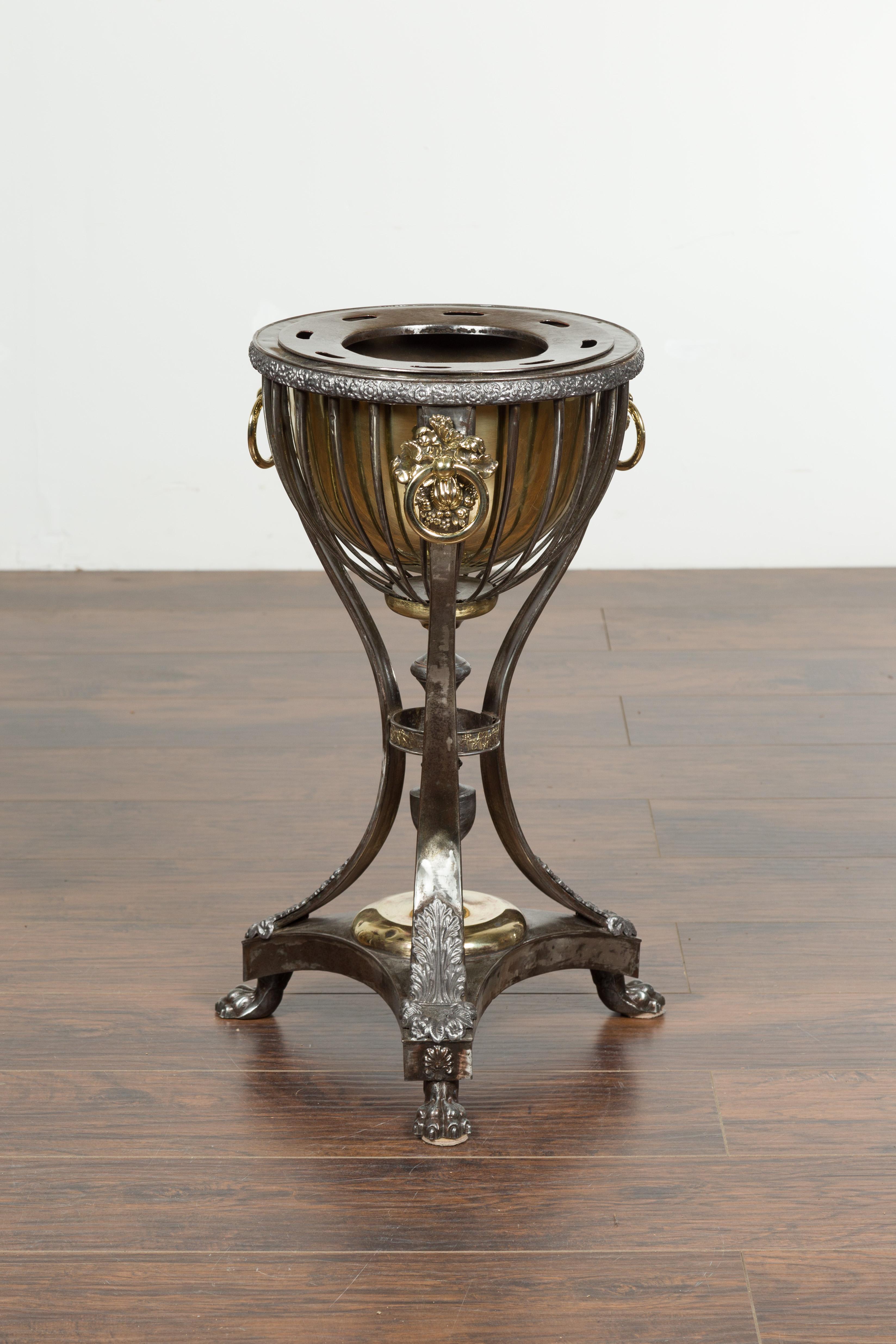 An English steel and brass wine cooler from the early 19th century, with foliage and fruit motifs and paw feet. Created in England during the first quarter of the 19th century, this wine cooler attracts our attention with its contrasting colors and