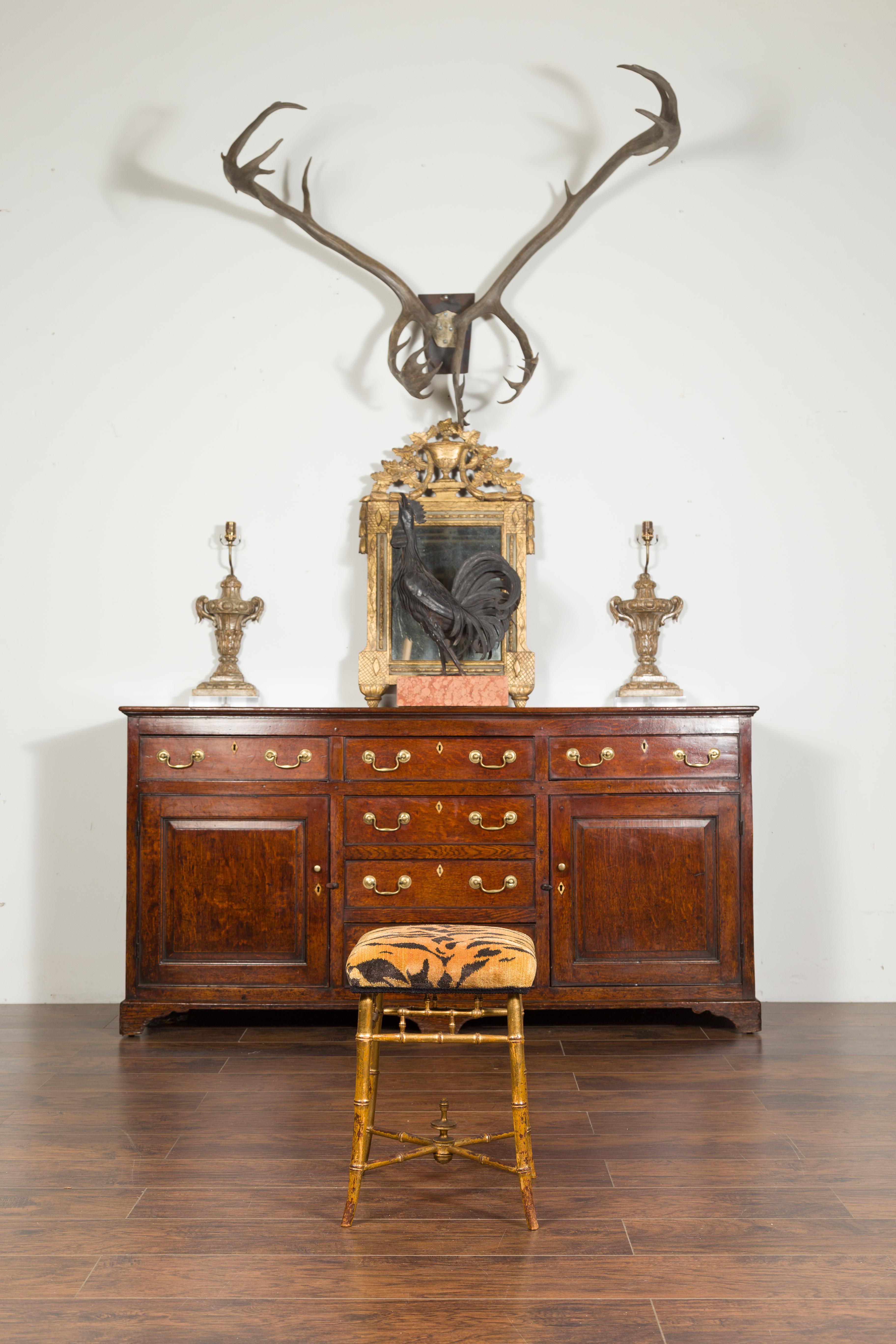 An English Chinese Chippendale style gilt faux bamboo stool from the mid-19th century, with new tiger print upholstery, saber legs and cross stretcher. Created in England during the second quarter of the 19th century, this Chinese Chippendale style