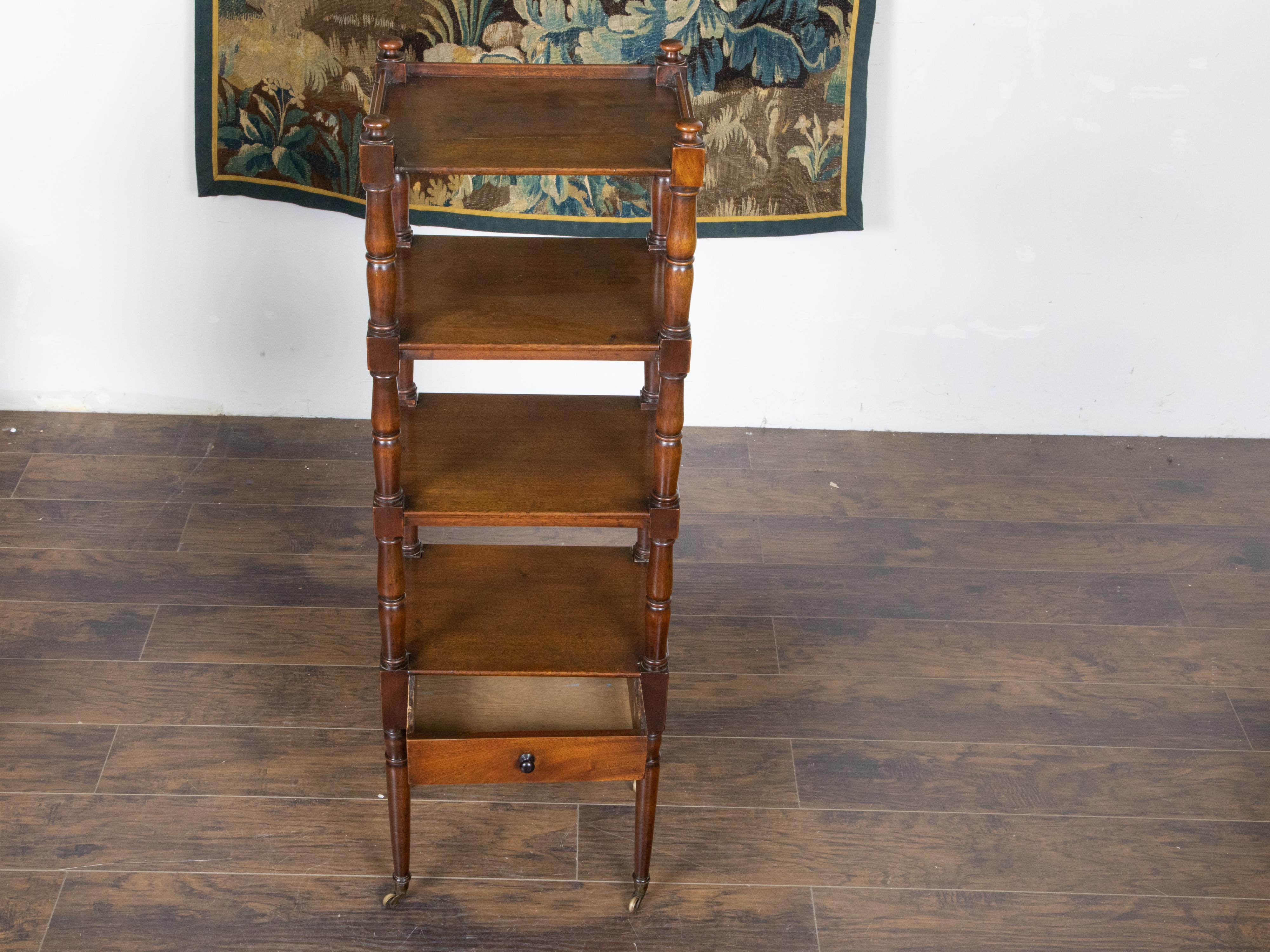 An English mahogany four-tiered trolley from the mid 19th century, with turned side posts, low drawer, finials and petite casters. Created in England during the second quarter of the 19th century, this mahogany trolley features four rectangular