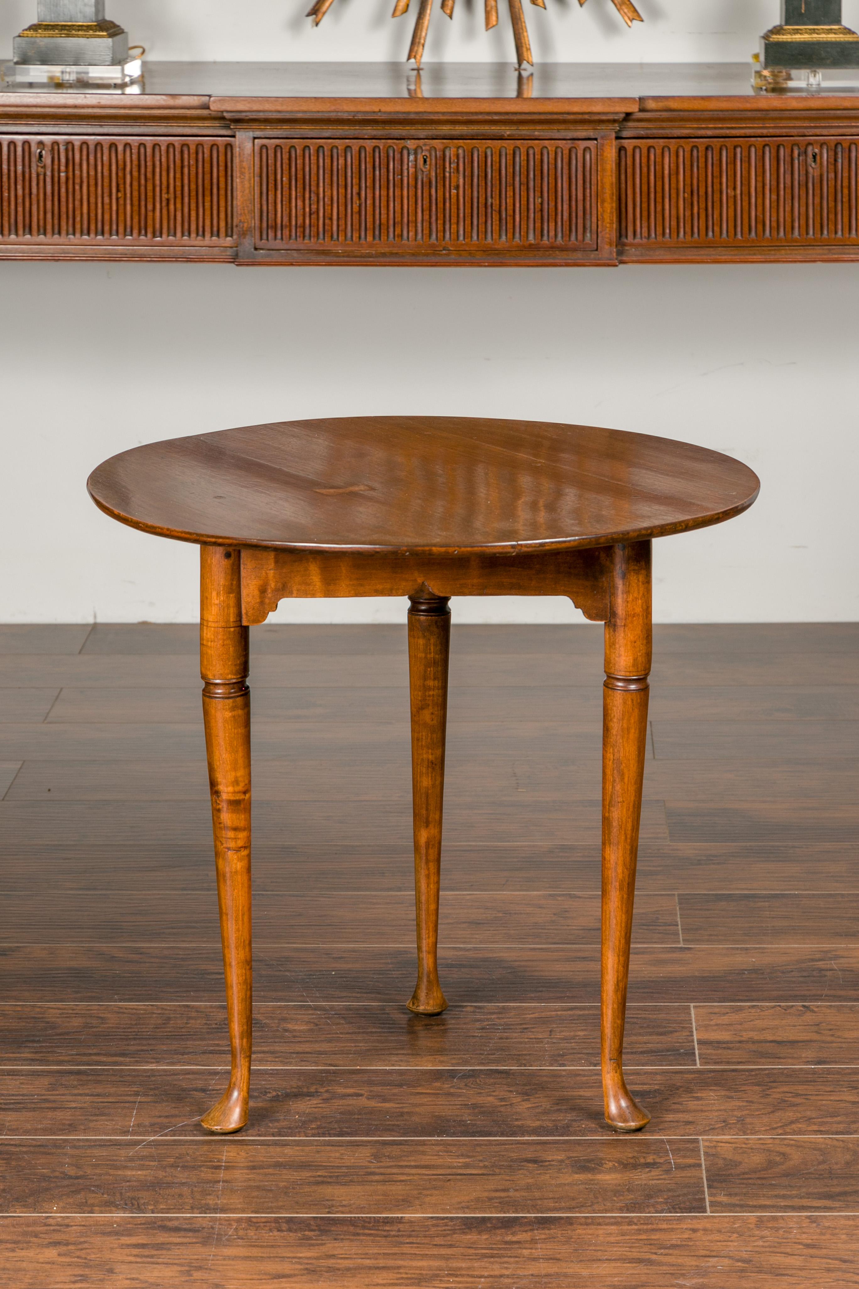 An English mahogany table from the mid-19th century, with circular top and pad feet. Created in England during the second quarter of the 19th century, this mahogany table features a round top sitting above a triangular apron. The table is raised on