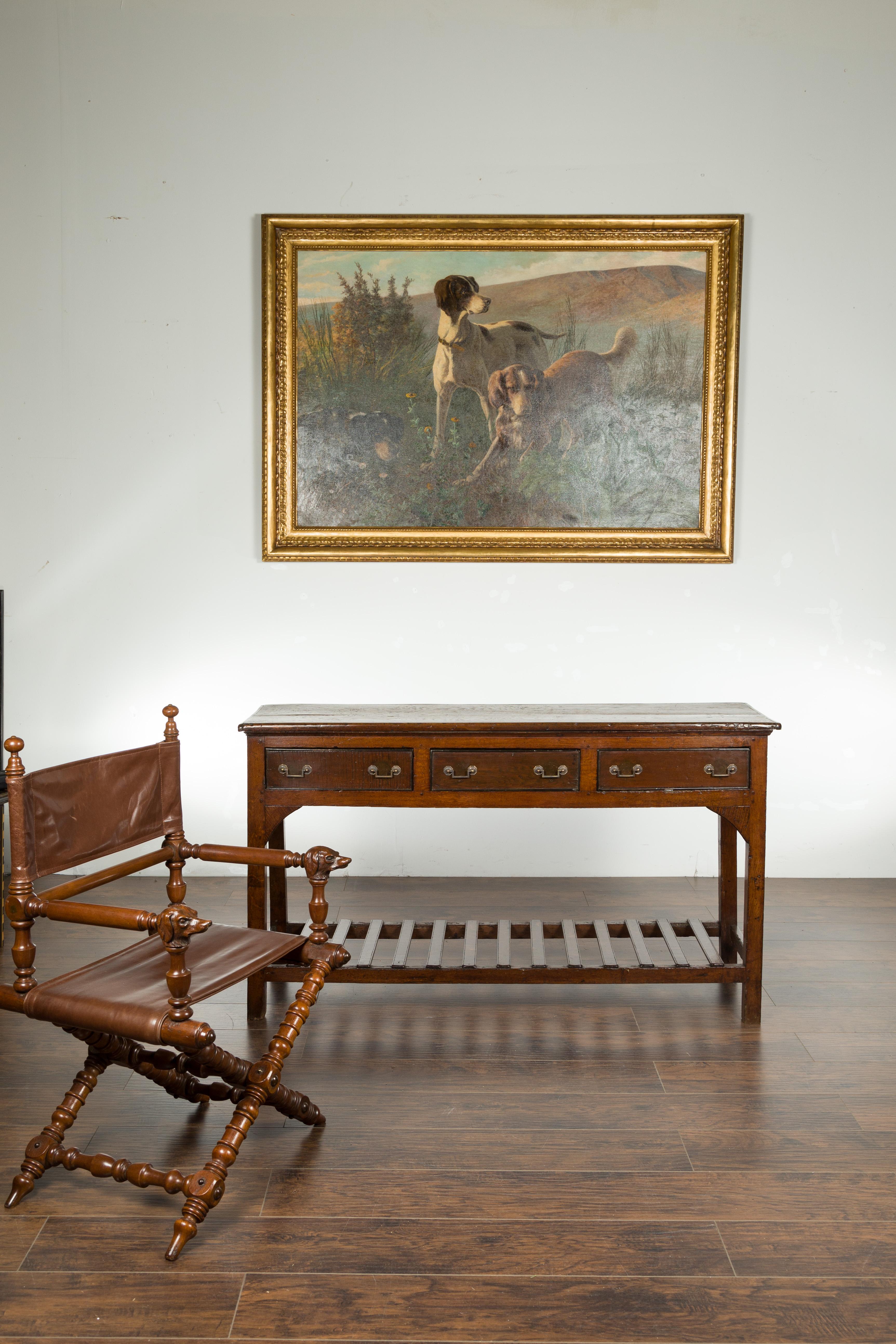 An English oak dresser base from the mid 19th century, with three drawers and lower slatted shelf. Created in England during the second quarter of the 19th century, this oak dresser base features a rectangular planked top sitting above three drawers