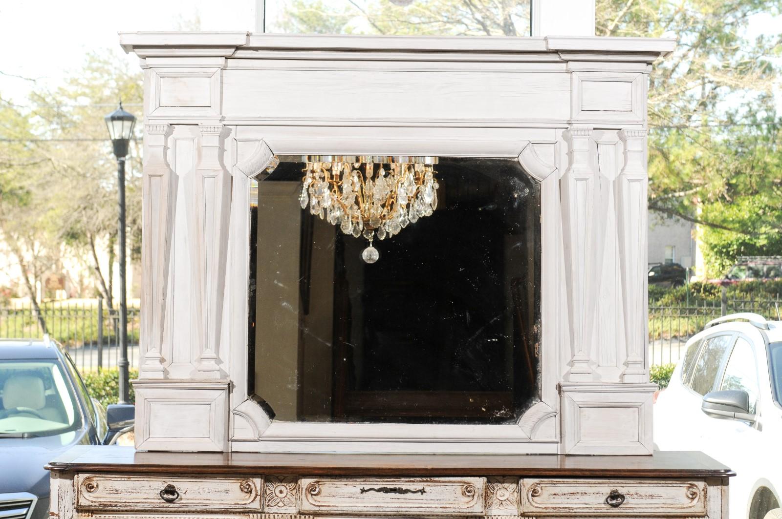 An English painted wood over mantel mirror from the mid-19th century, with classical tapering pilasters and bevelled glass. Born in the early years of Queen Victoria's reign, this elegant over mantel mirror features a linear light painted body