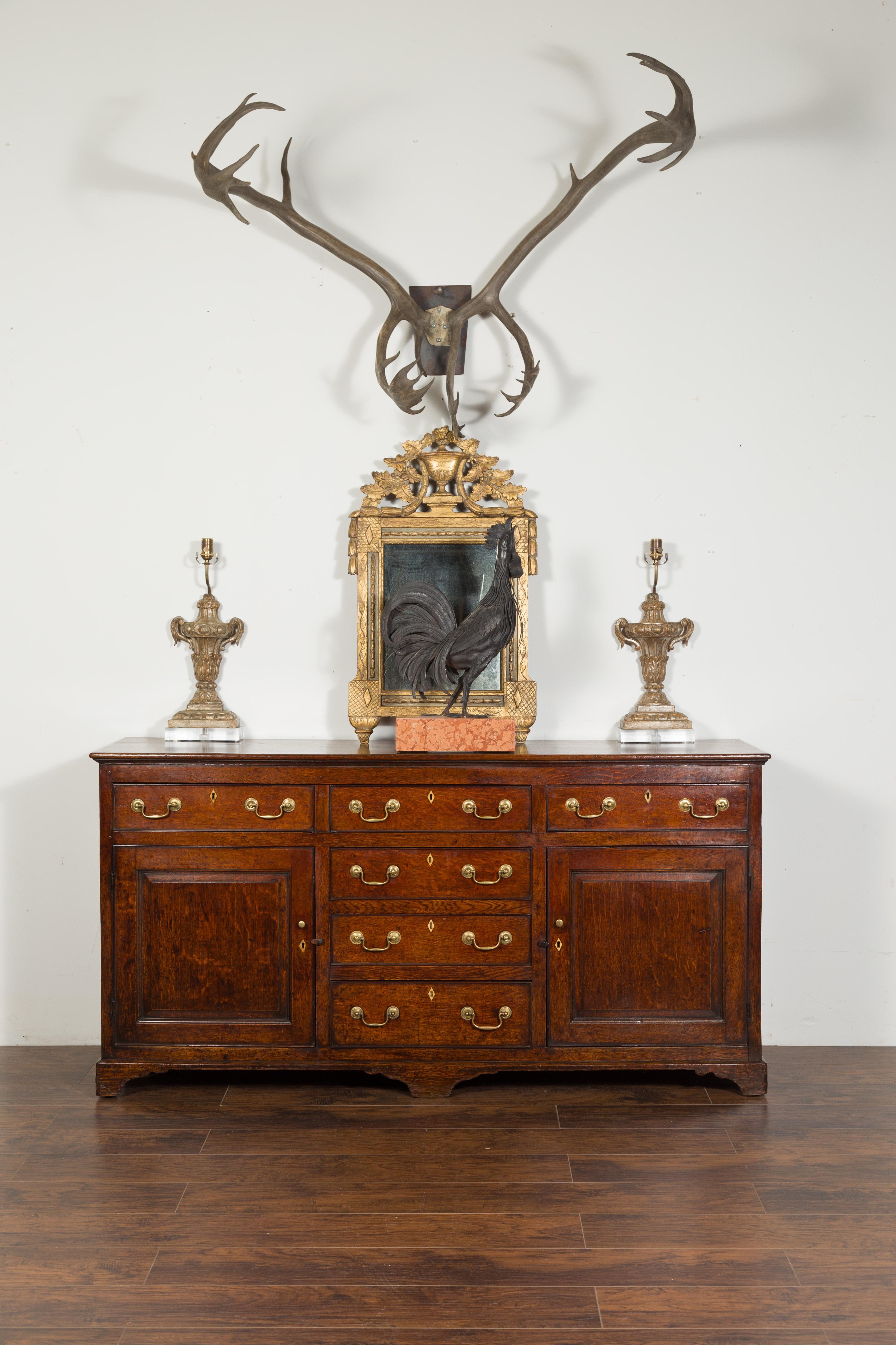 An English oak dresser base / server from the mid-19th century, with brass hardware and bone inlay. Created in England during the 1850s, this oak dresser base / server features a rectangular top sitting above a perfectly organized façade. Six