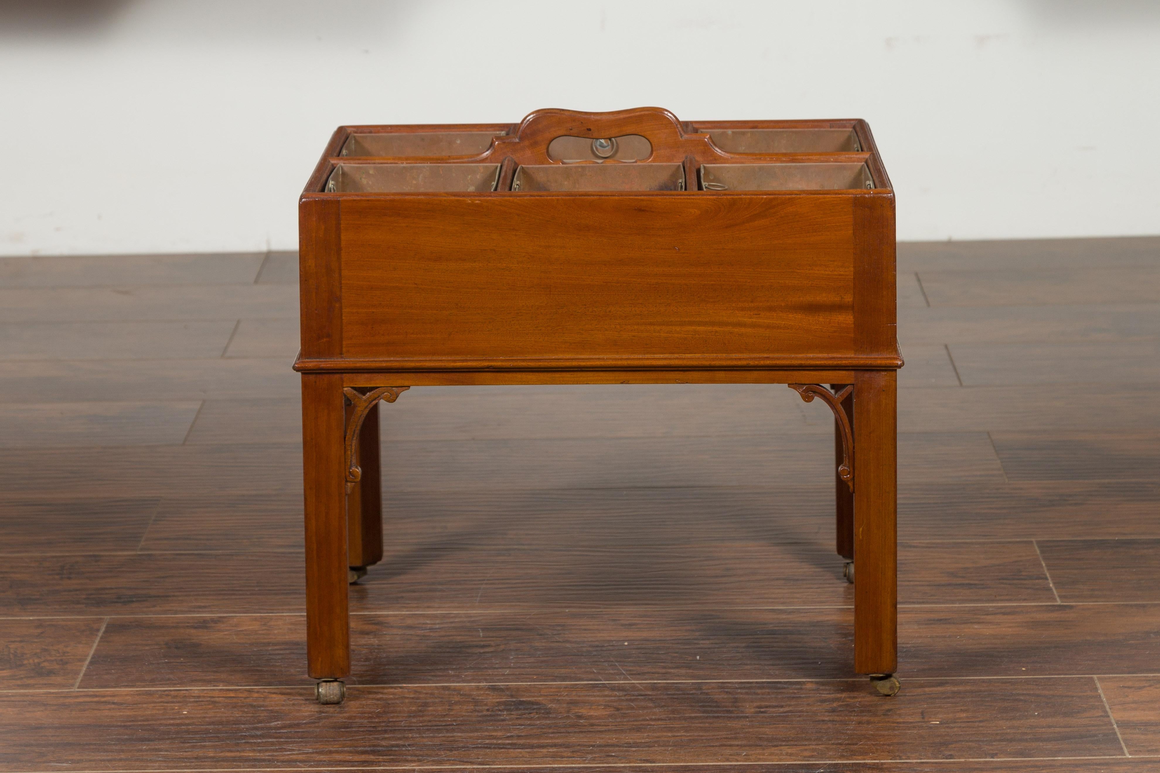 An English mahogany copper lined wine caddy from the mid-19th century, with carved spandrels and casters. Created in England during the third quarter of the 19th century, this wine caddy features a rectangular partitioned top securing six removable