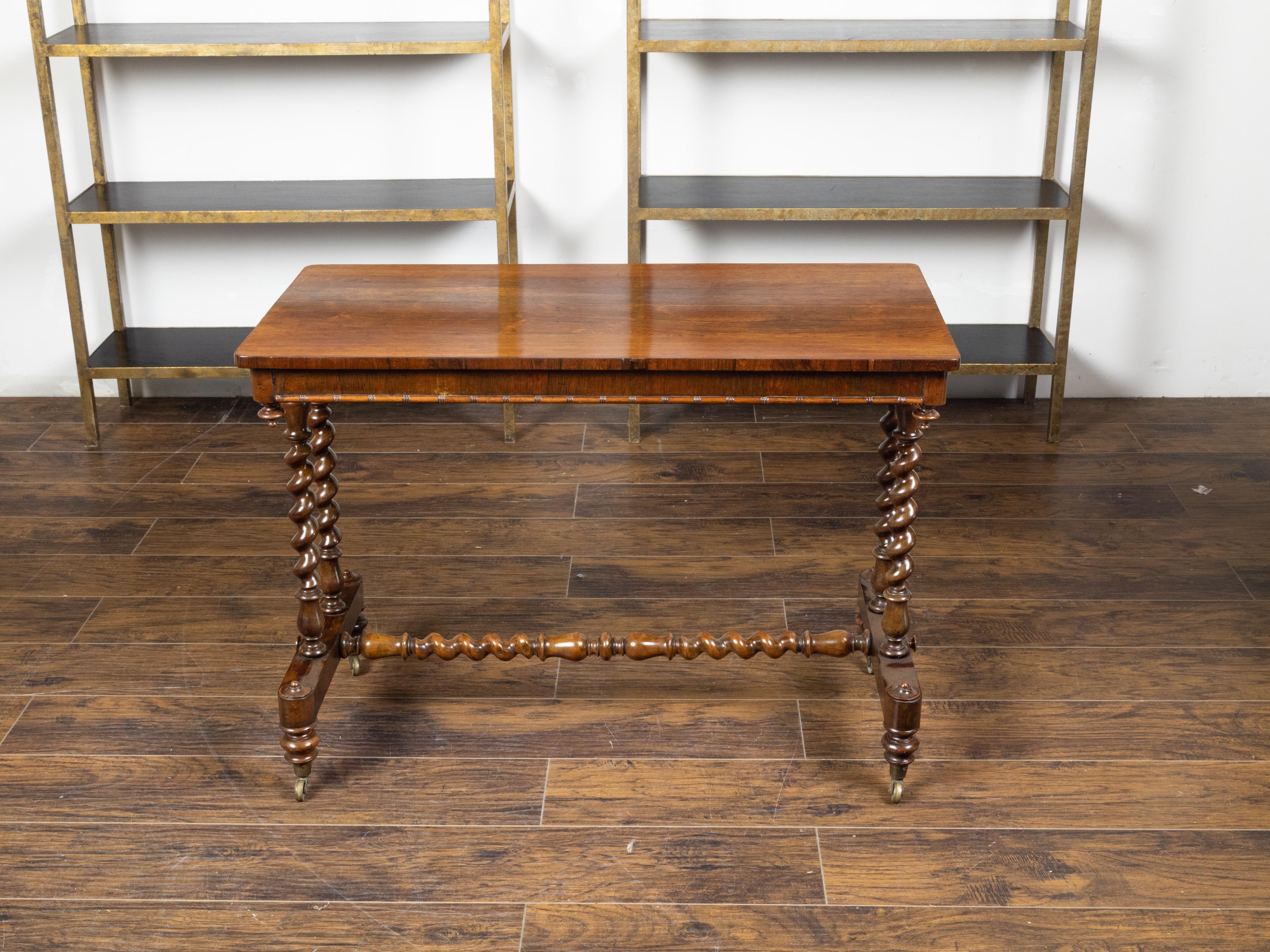 An English mahogany table from the mid 19th century, with barley twist base and casters. Created in England during the third quarter of the 19th century, this mahogany table features a rectangular top with inverted finials on the apron's corners,