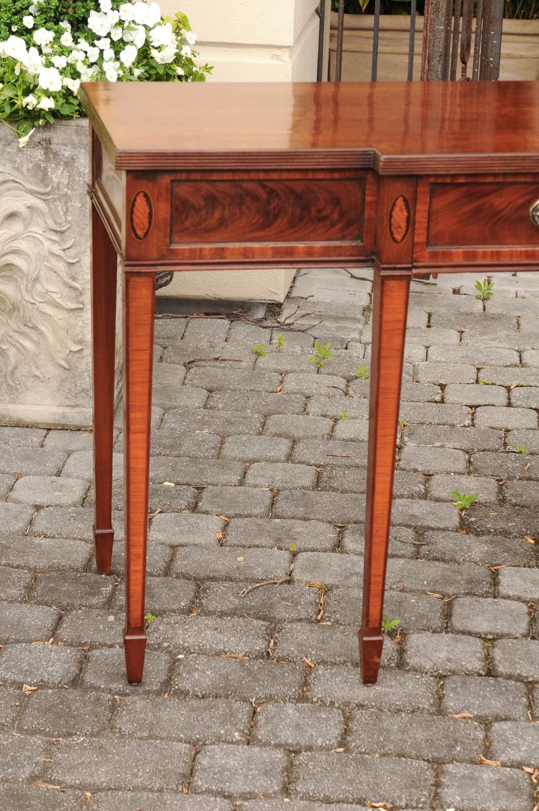 An English Neoclassical style mahogany breakfront sideboard server from the mid 19th century with flaming accents, long single drawer and tapered legs. Born in England during the third quarter of the 19th century, this exquisite breakfront server
