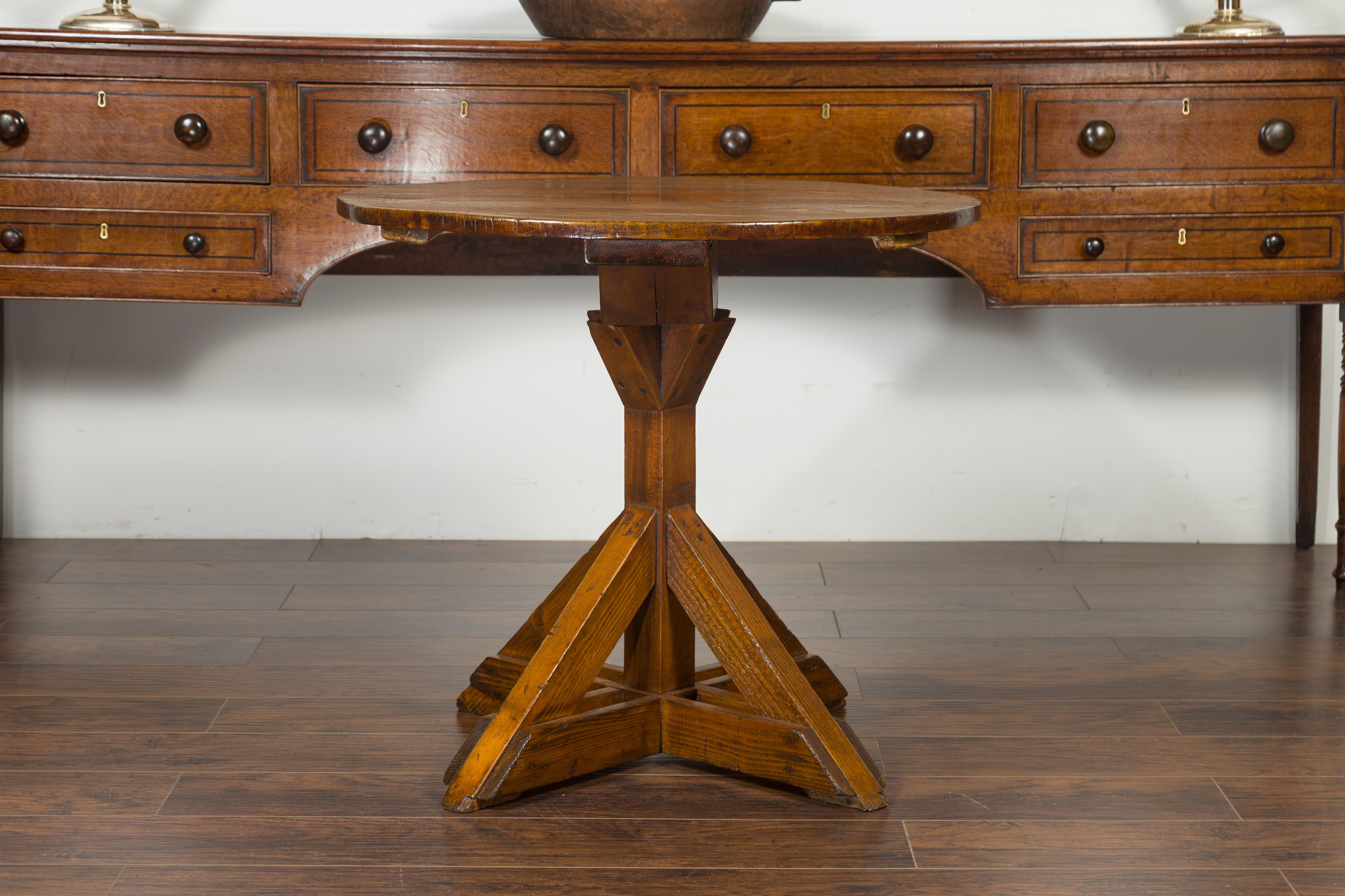 An English oak and pine sawbuck base side table from the mid-19th century, with circular top. Created in England during the third quarter of the 19th century, this rare oak and pine side table features a circular top sitting above a sawbuck base.