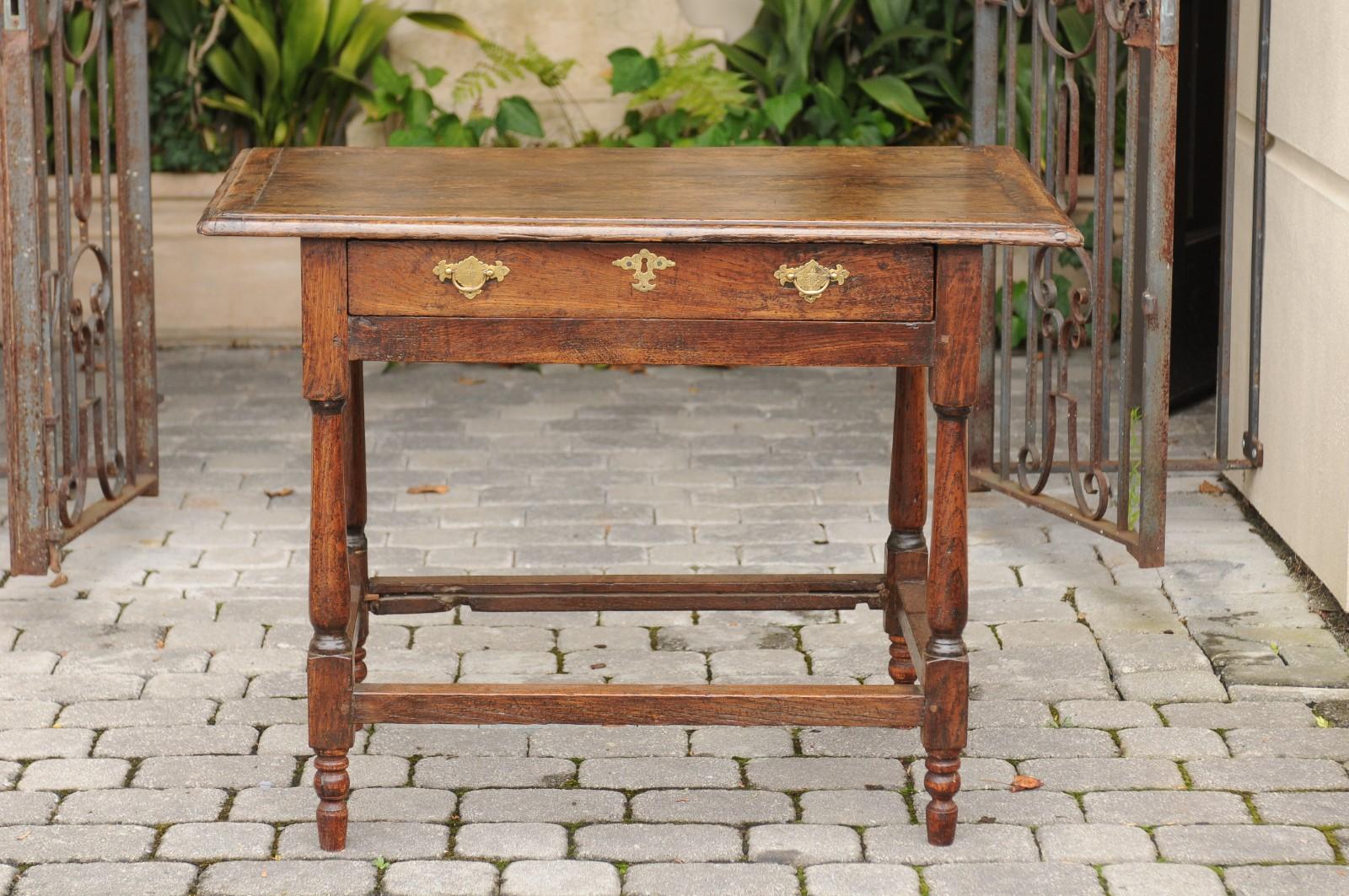 An English oak side table from the mid-19th century with single drawer, turned baluster legs and side stretcher. Born during the third quarter of the 19th century, this English side table features a rectangular planked top sitting above a frieze