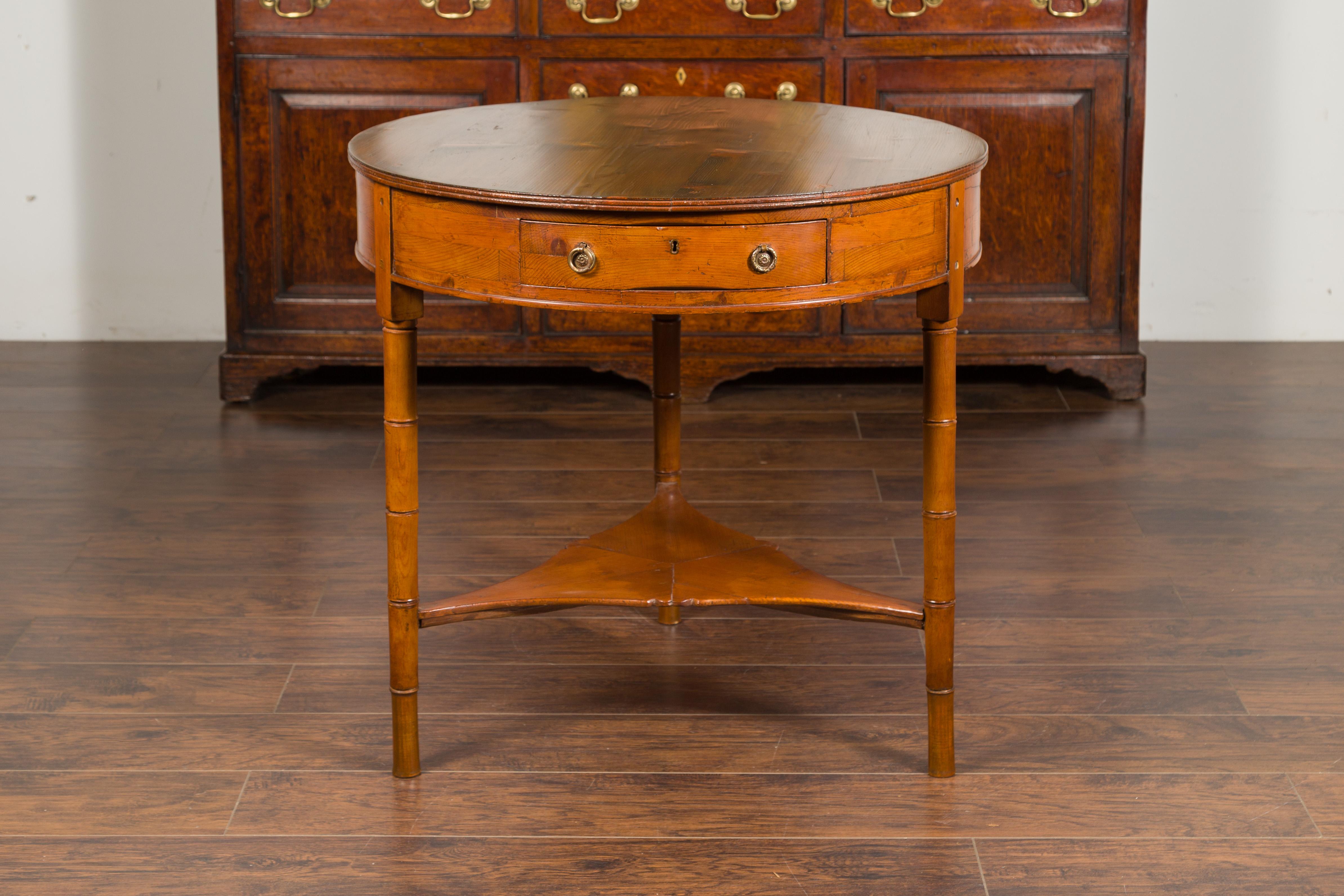 An English pine center table from the mid-19th century, with partitioned drawer, faux bamboo legs and triangular shelf. Created in England during the last third of the 19th century, this center table features a circular top resting above a single