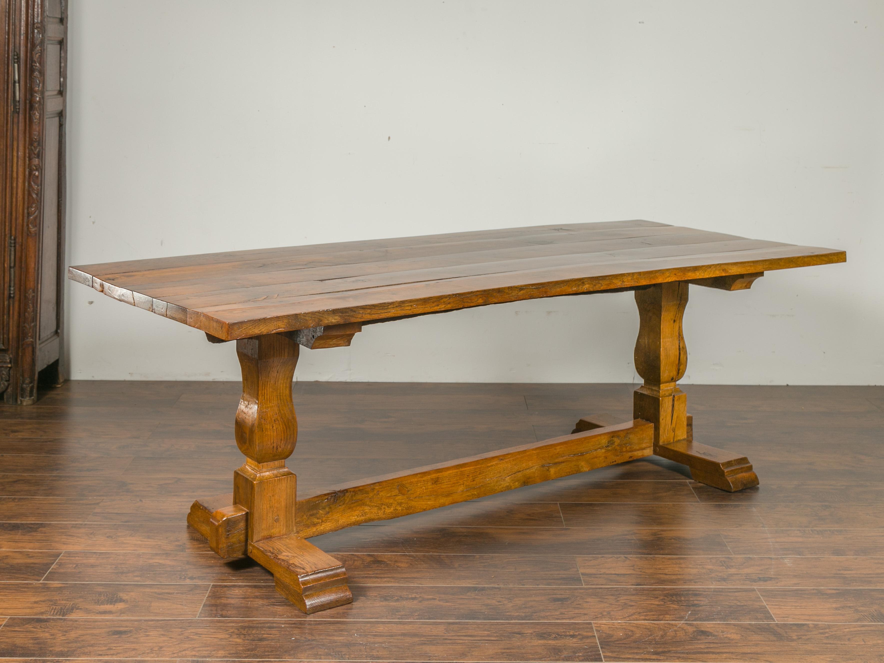 An English elm and walnut farm table from the late 19th century, with trestle base. Born in England during the third quarter of the 19th century, this farm table features a rectangular planked top sitting above a trestle base showcasing baluster