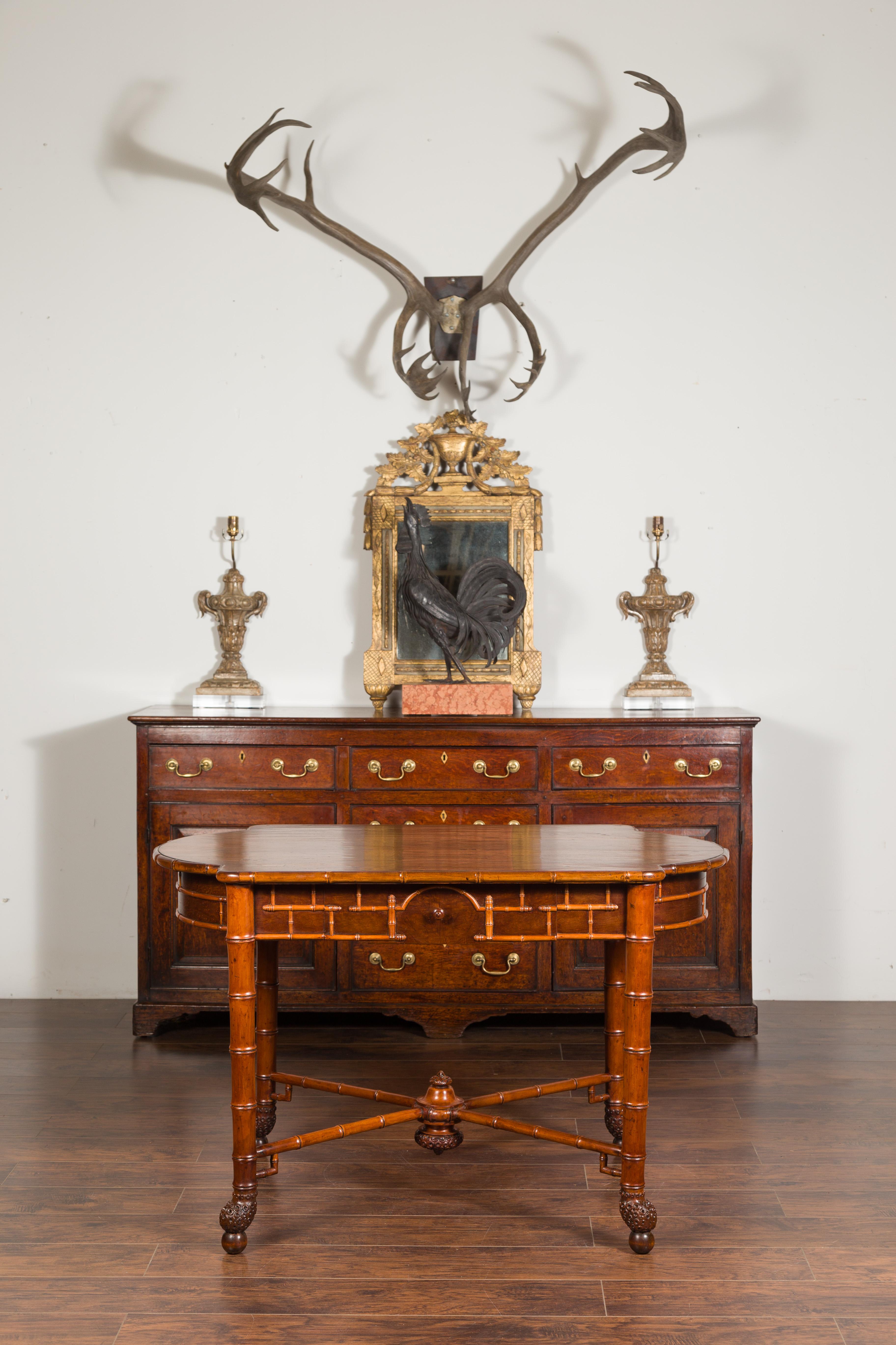 An English faux bamboo walnut desk from the late 19th century, with oval shaped top, two drawers and bamboo root style feet. Created in England during the third quarter of the 19th century, this walnut desk attracts our attention with its faux