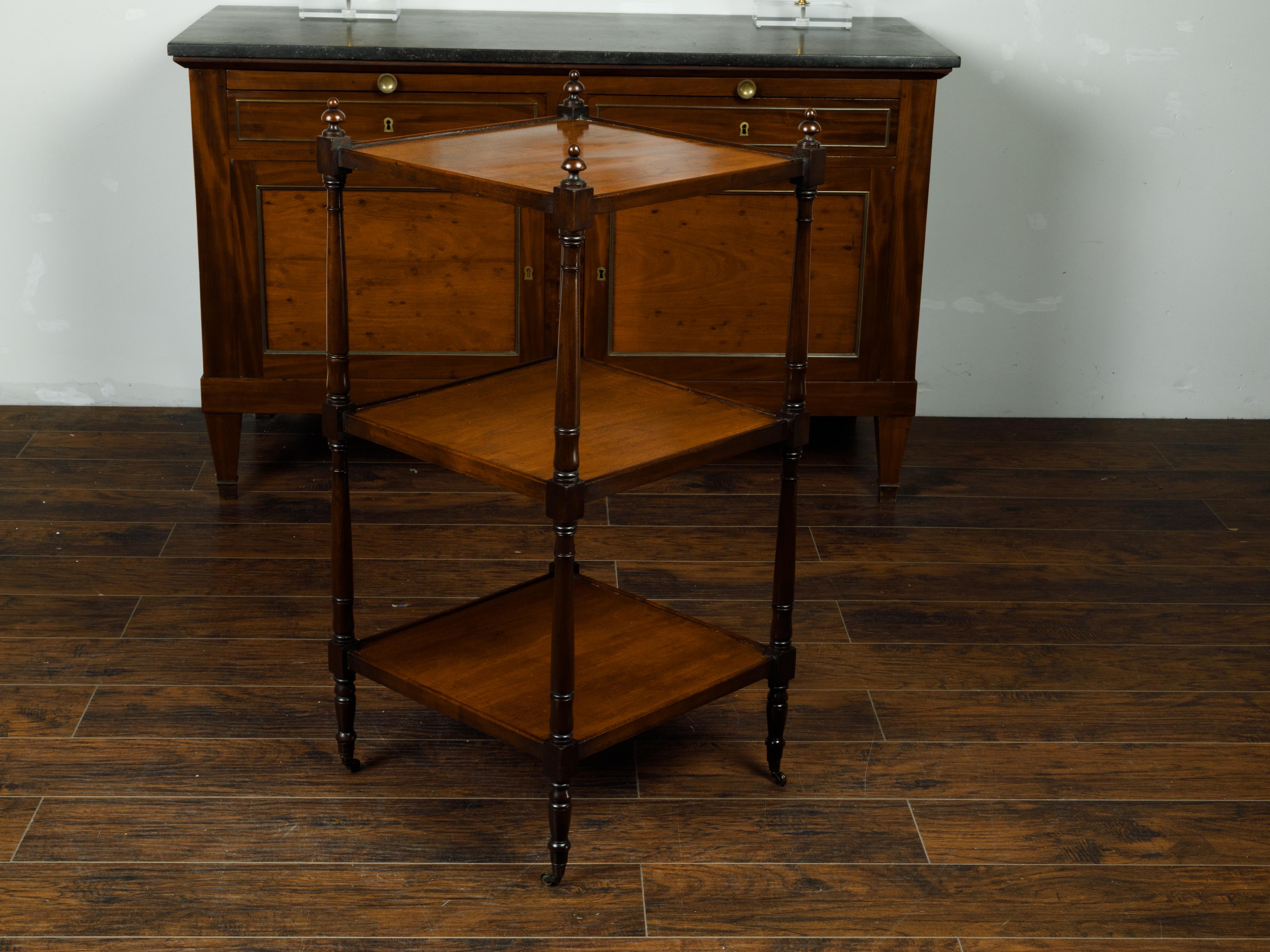 An English mahogany three-tiered trolley from the late 19th century, with turned side posts and finials. Created in England during the third quarter of the 19th century, this mahogany trolley features three rectangular shelves secured within four