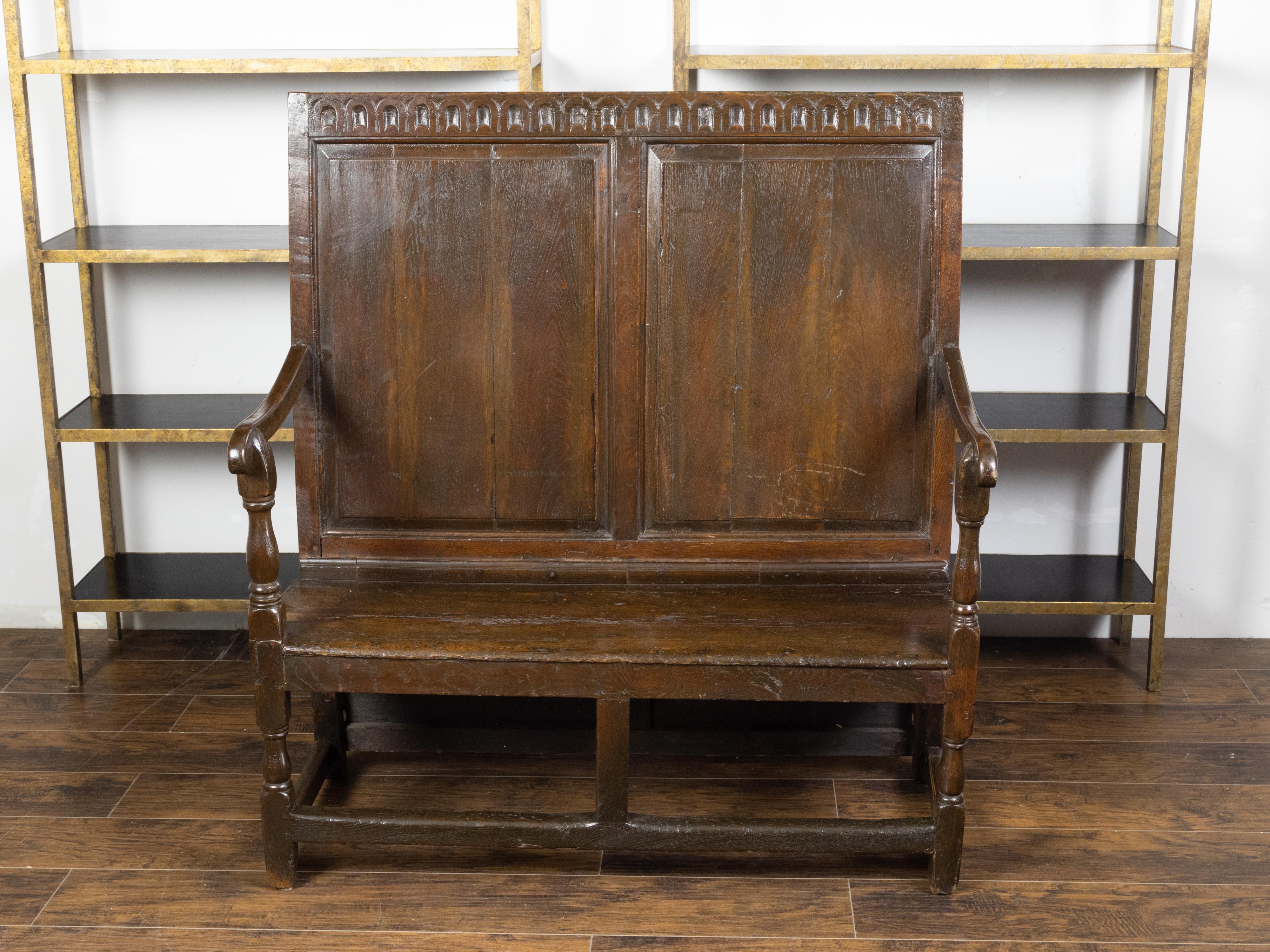 An English oak bench from the late 19th century, with carved frieze and scrolling arms. Created in England during the third quarter of the 19th century, this oak bench captures our attention with its nicely rustic appearance and simple lines.
