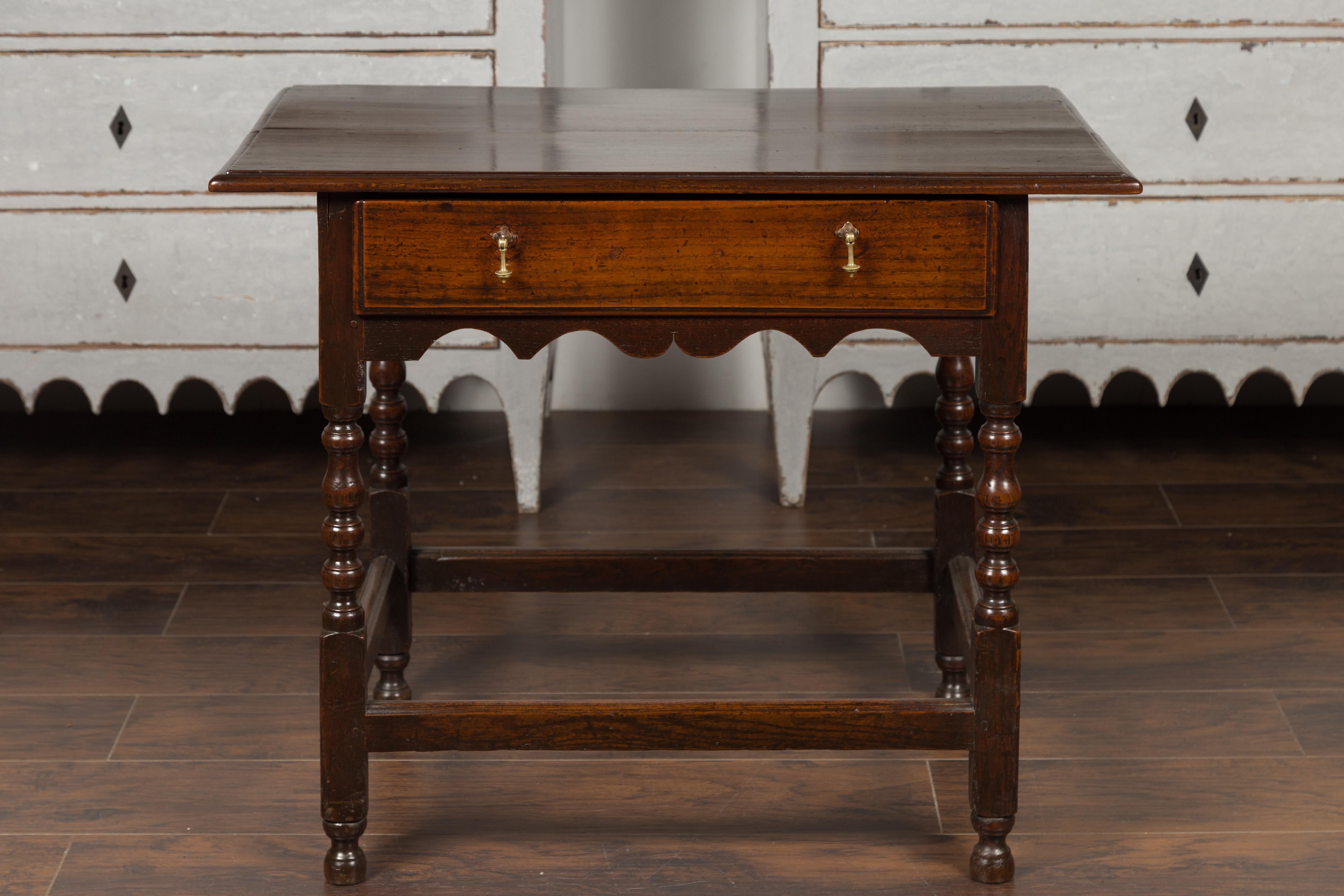 An English oak side table from the late 19th century, with single drawer, carved apron and turned legs. Crafted in England during the third quarter of the 19th century, this oak side table features a rectangular top with beveled edges, sitting above