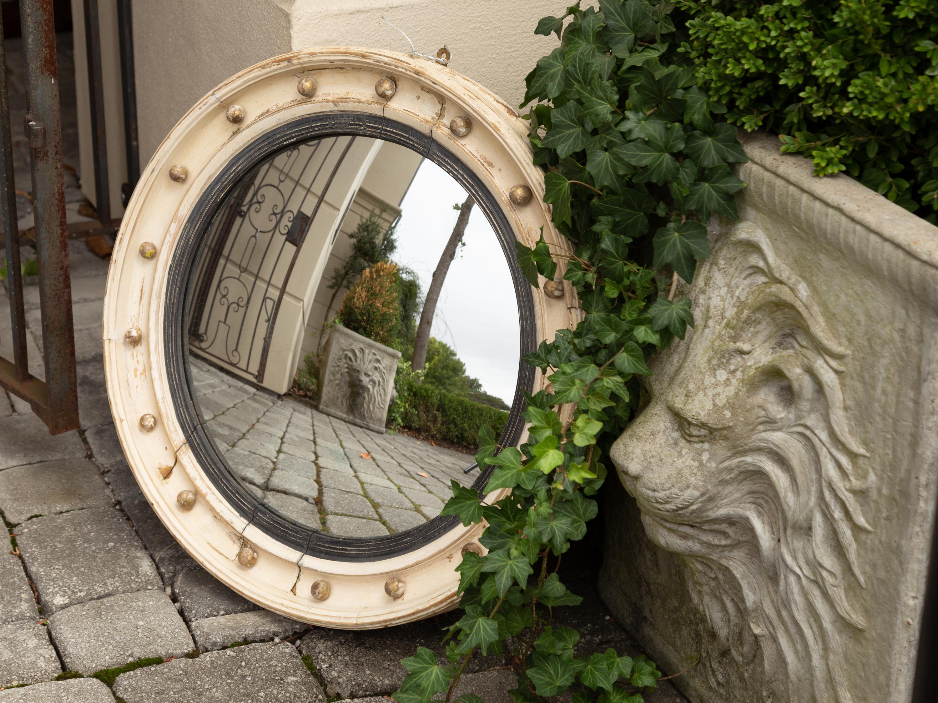 An English painted wood bullseye convex mirror from the late 19th century with ebonized reeded accents and distressed finish. Born in England during the third quarter of the 19th century, this stylish circular mirror features a convex mirror plate,