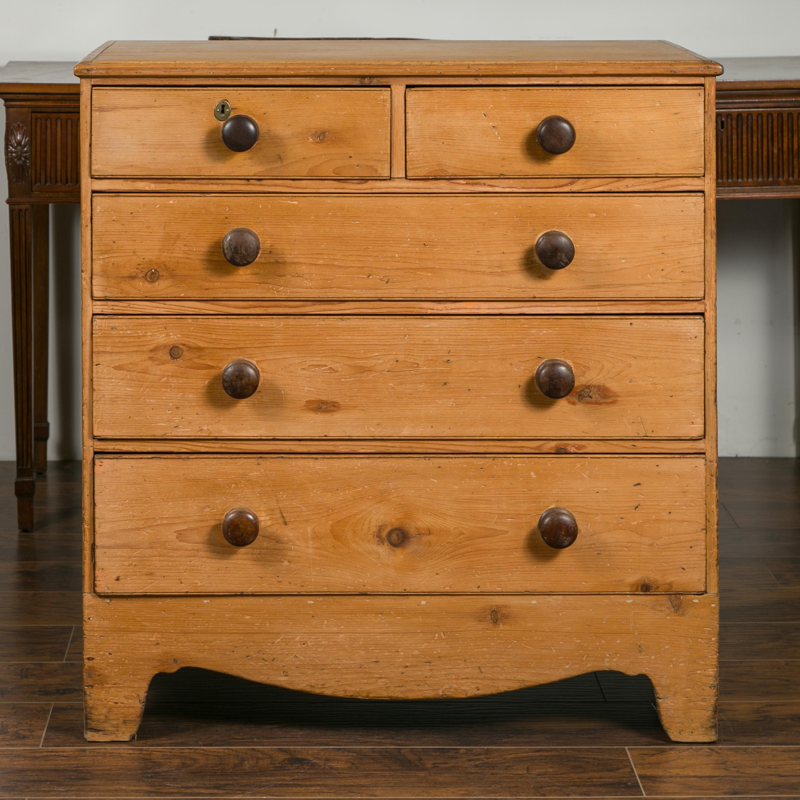 An English pine chest from the late 19th century with five drawers, valanced apron and wooden pulls. Created in England during the third quarter of the 19th century, this pine chest features a simple rectangular top sitting above five dovetailed
