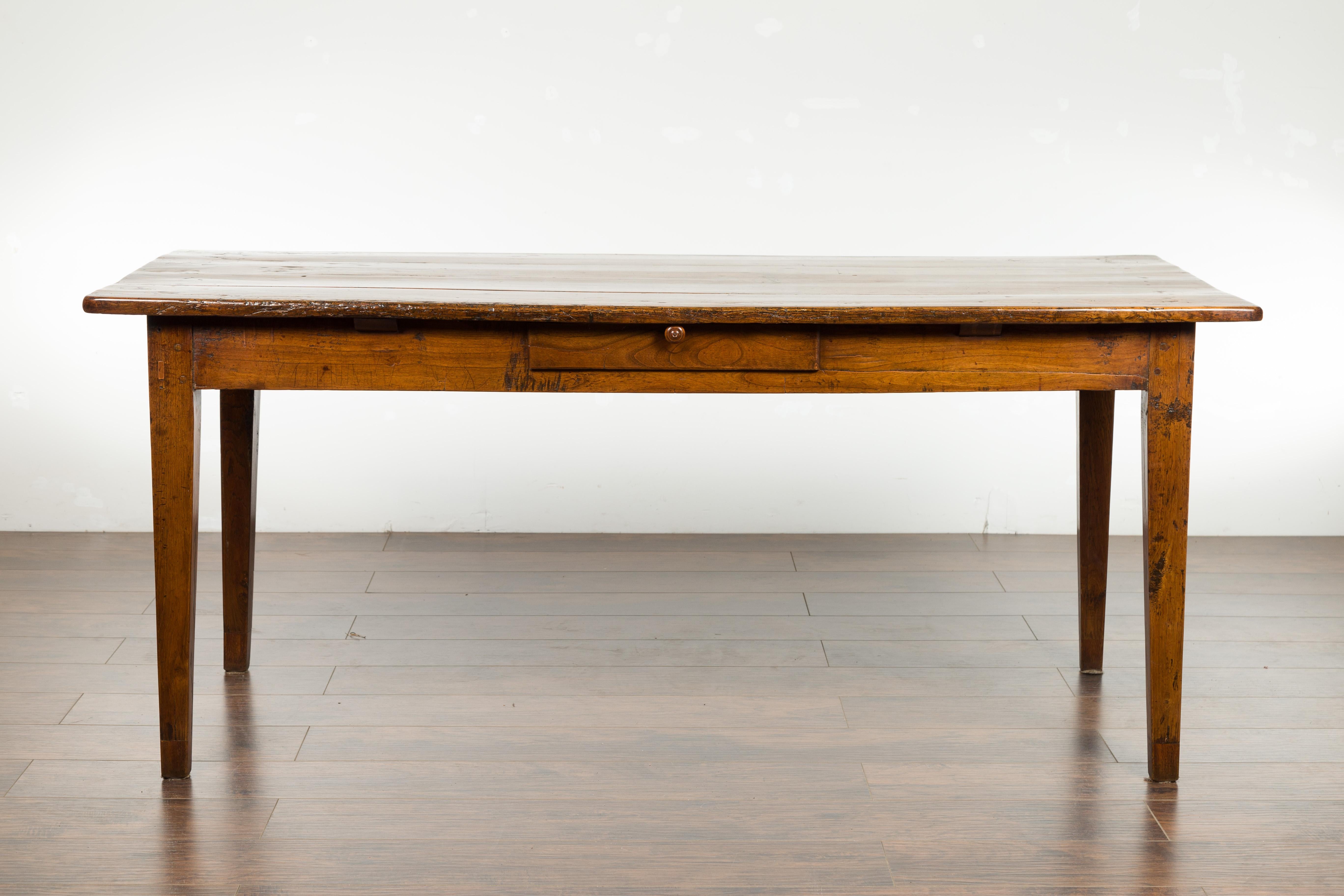 An English elm farm table from the late 19th century, with single drawer and tapered legs. Created in England during the third quarter of the 19th century, this elm farm table, which could be used as a desk as well, features a rectangular planked