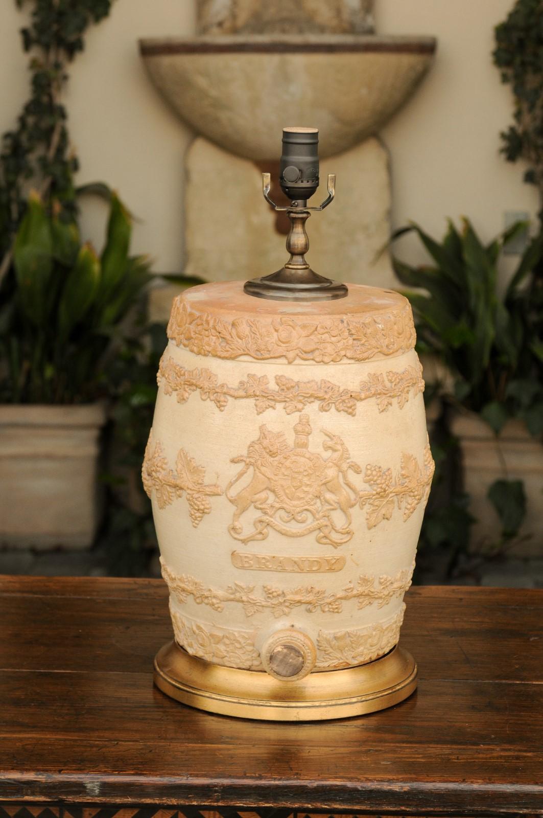 An English stoneware spirit barrel from the late 19th century, with the United Kingdom’s royal coat of arms and mounted as a table lamp. Born in England during the third quarter of the 19th century, this English stoneware spirit barrel has been