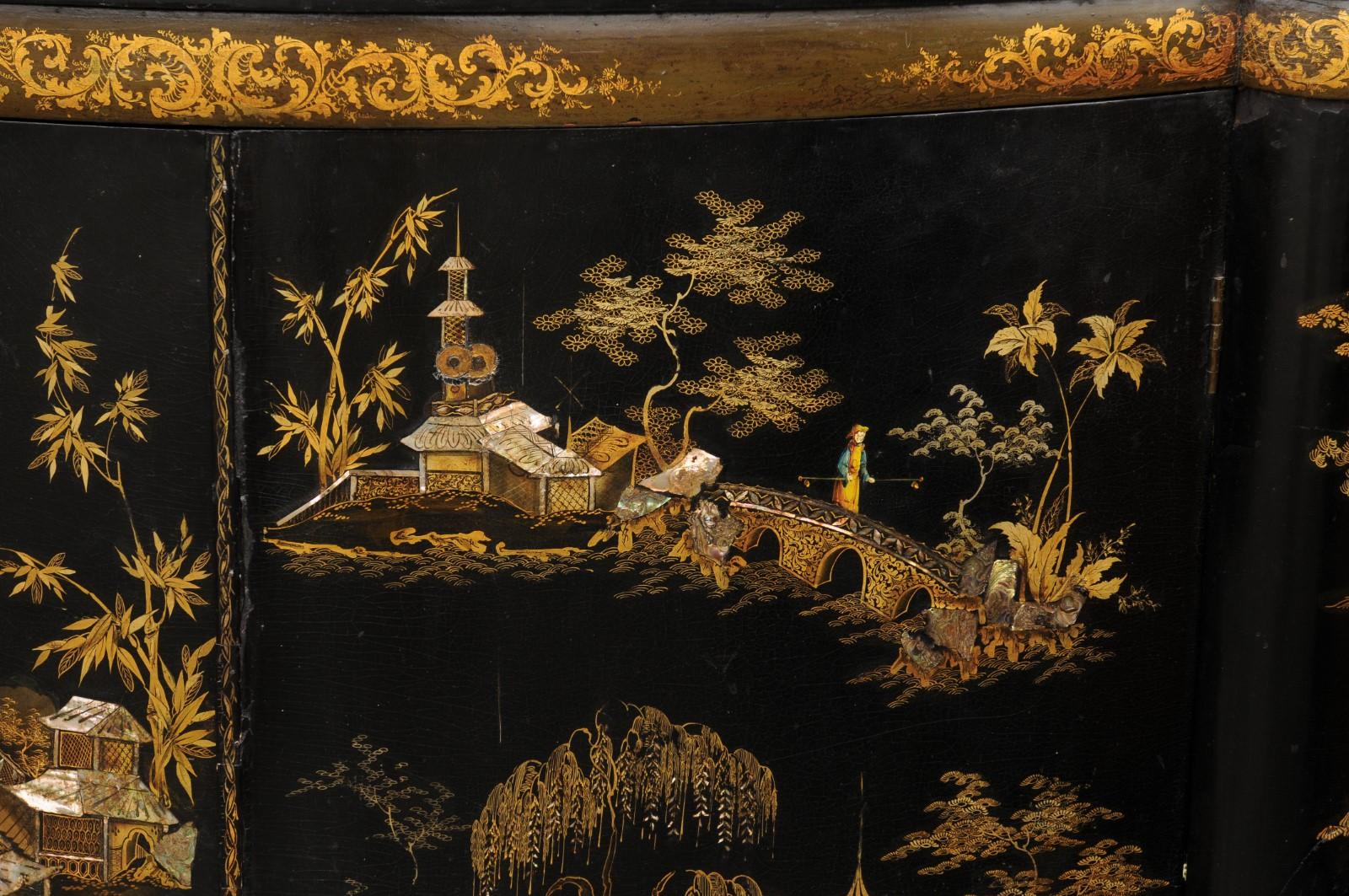 An English black lacquered narrow two-door credenza from the late 19th century, with gilt chinoiserie décor and serpentine side panels. Born in England during the later years of the 19th century, this exquisite credenza features a black top,