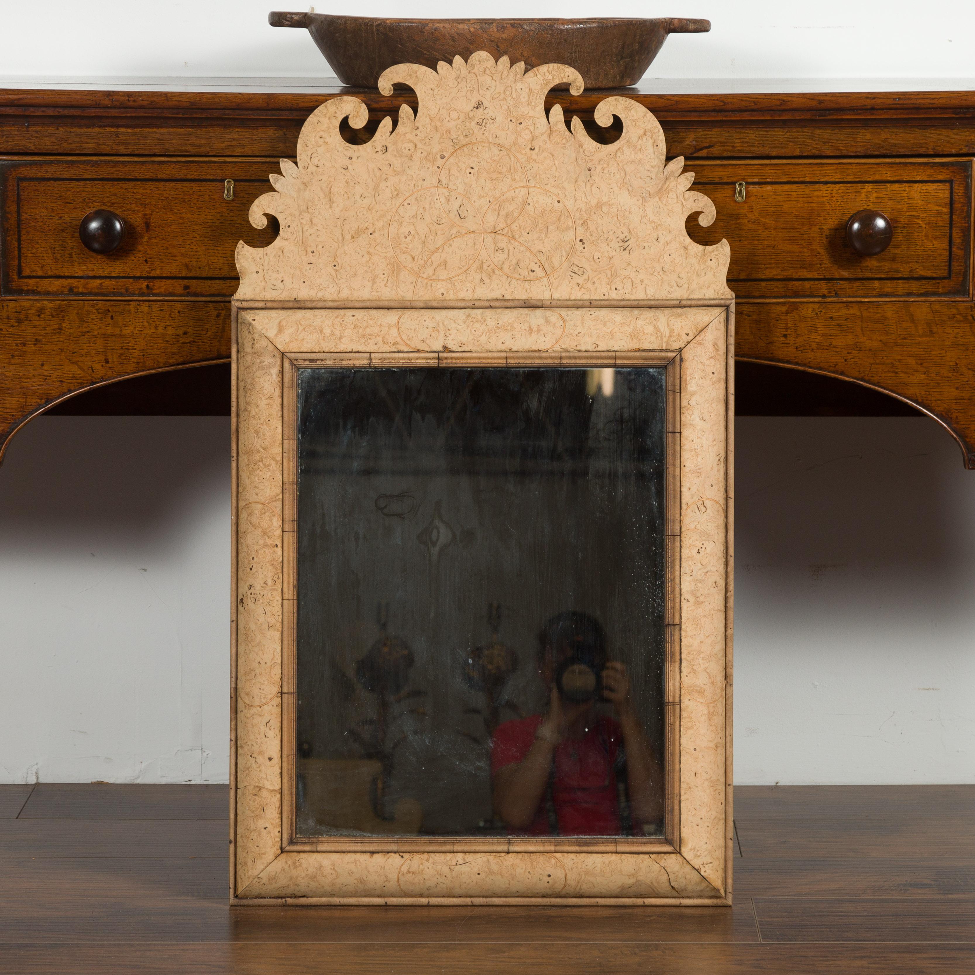 An English burl wood mirror from the late 19th century, with carved crest and beveled frame. Created in England during the last decade of the 19th century, this burl wood mirror attracts our immediate attention with its stunning carved crest