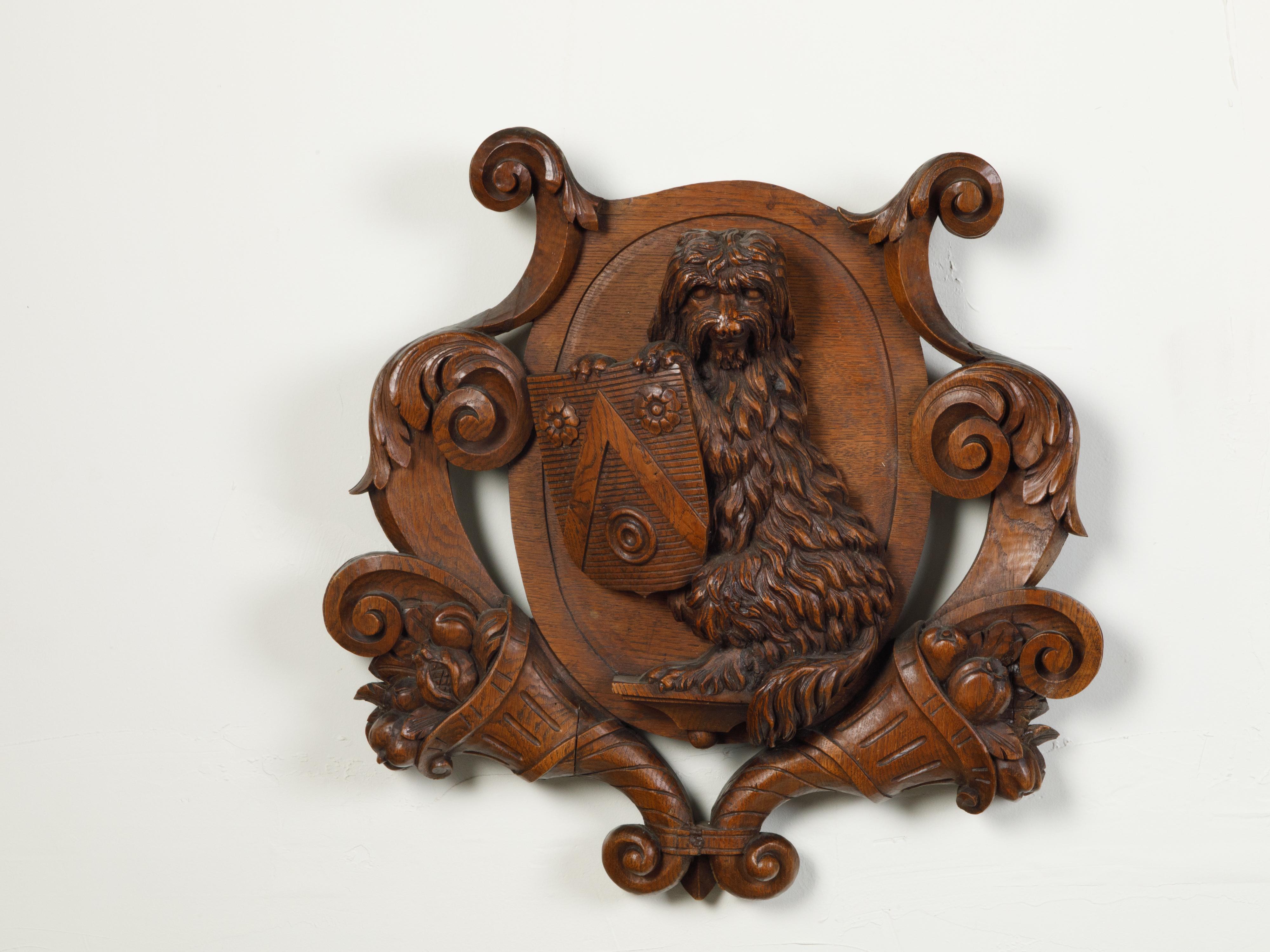 An English carved wooden wall fragment from the late 19th century, depicting a dog with a shield and cornucopia. Created in England during the last quarter of the 19th century, this wooden cartouche captures our attention with its skillful depiction