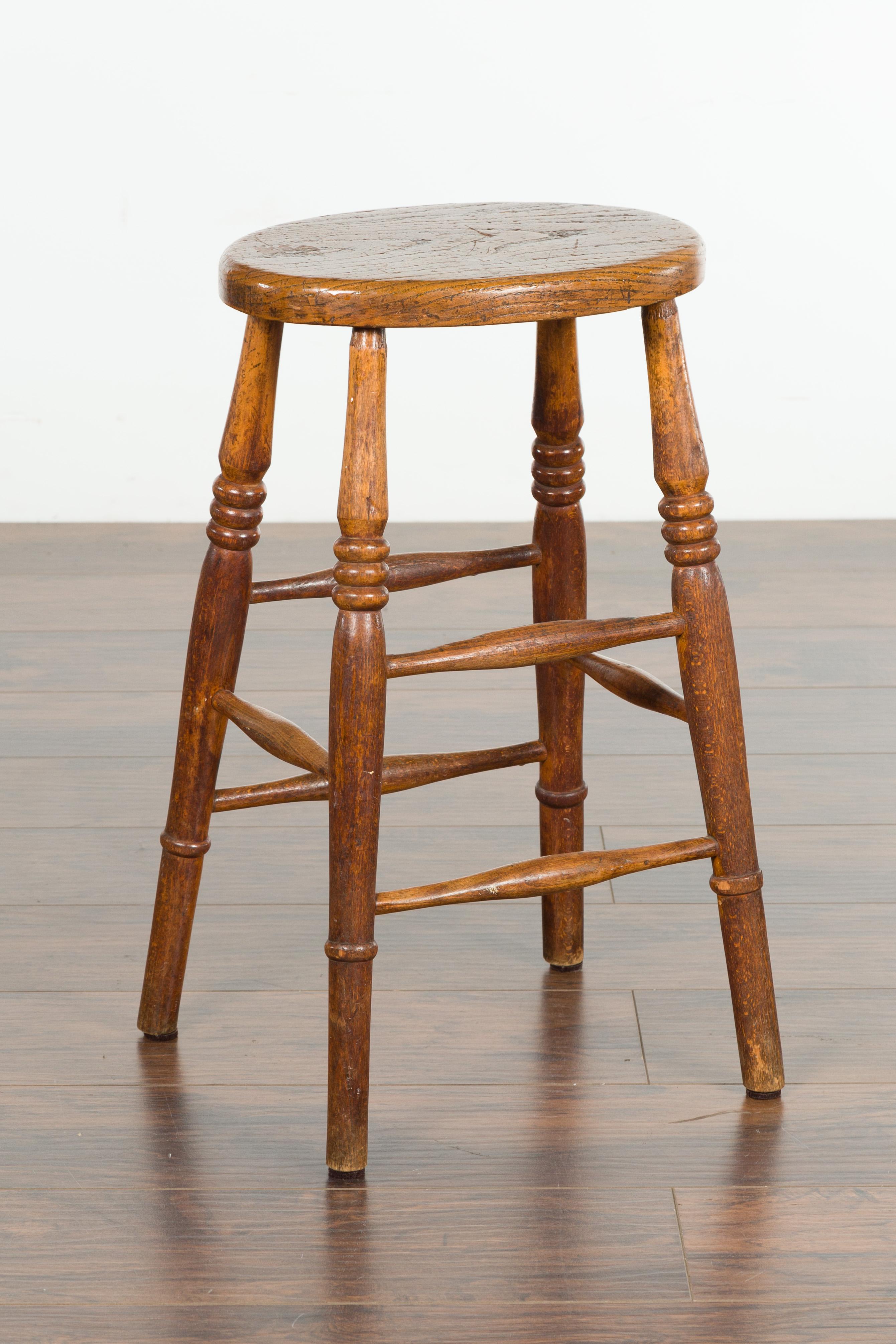 An English elm stool from the late 19th century, with oval seat and turned legs. Created in England during the last quarter of the 19th century, this elm stool charms us with its rustic appearance. An oval seat (measuring 14
