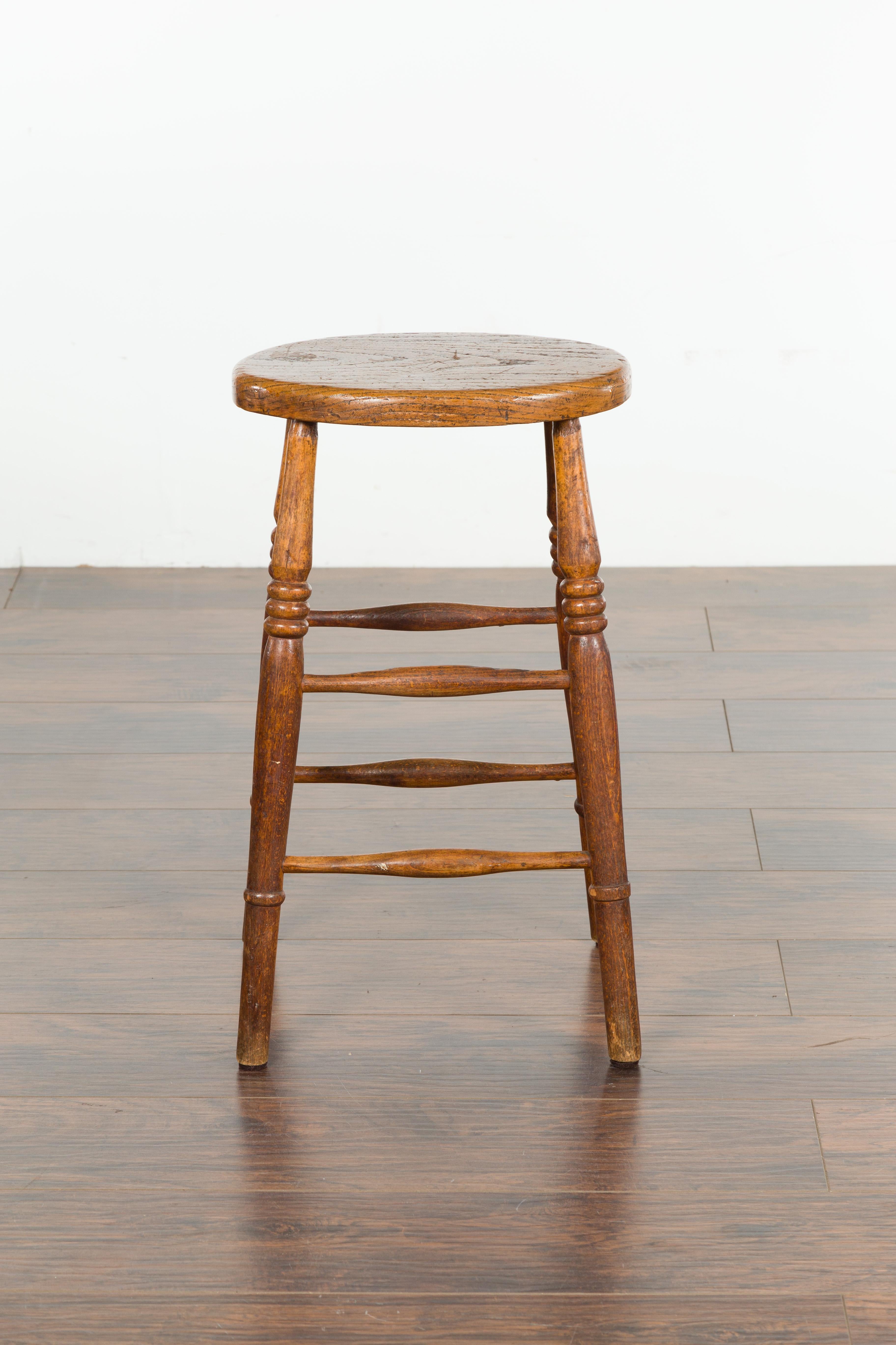 Rustic English 1880s Elm Stool with Oval Seat, Turned Splaying Legs and Side Stretchers