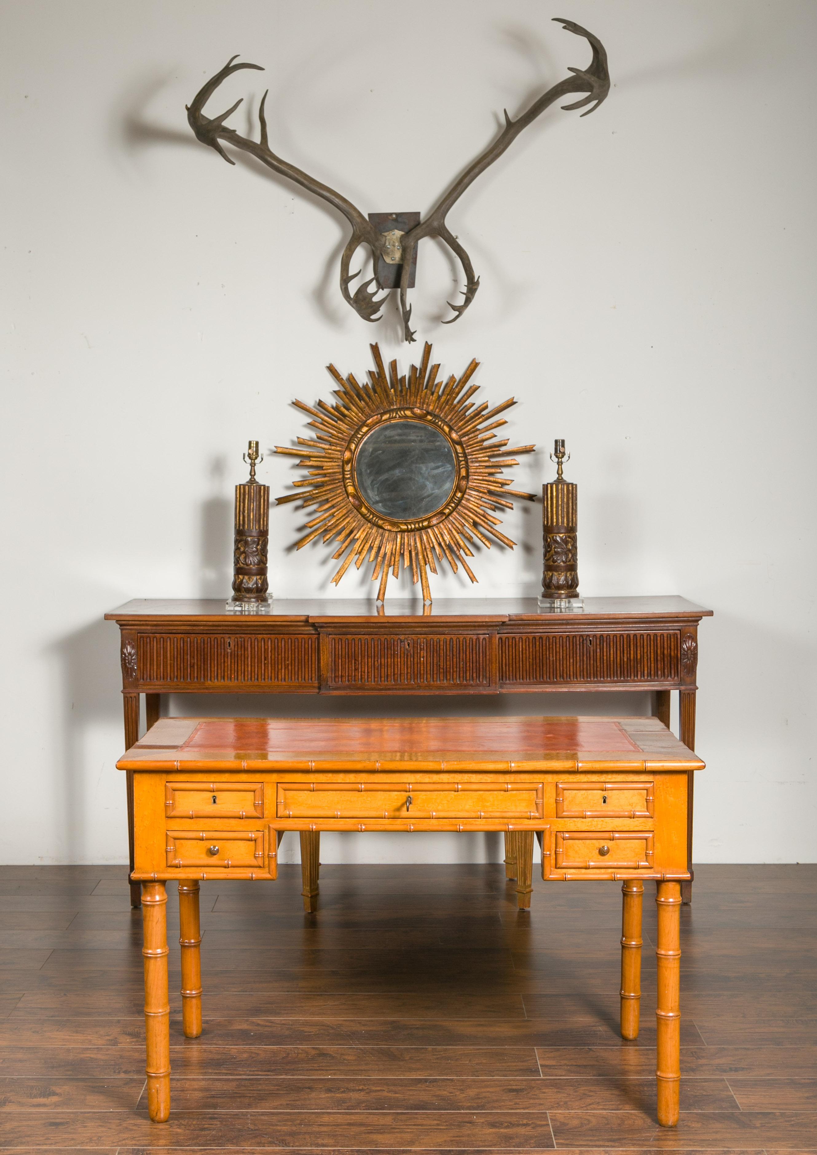 An English faux bamboo desk from the late 19th century, with copper leather top and five drawers. Created in England during the later years of the 19th century, this desk features a rectangular top with copper colored leather inset, resting above
