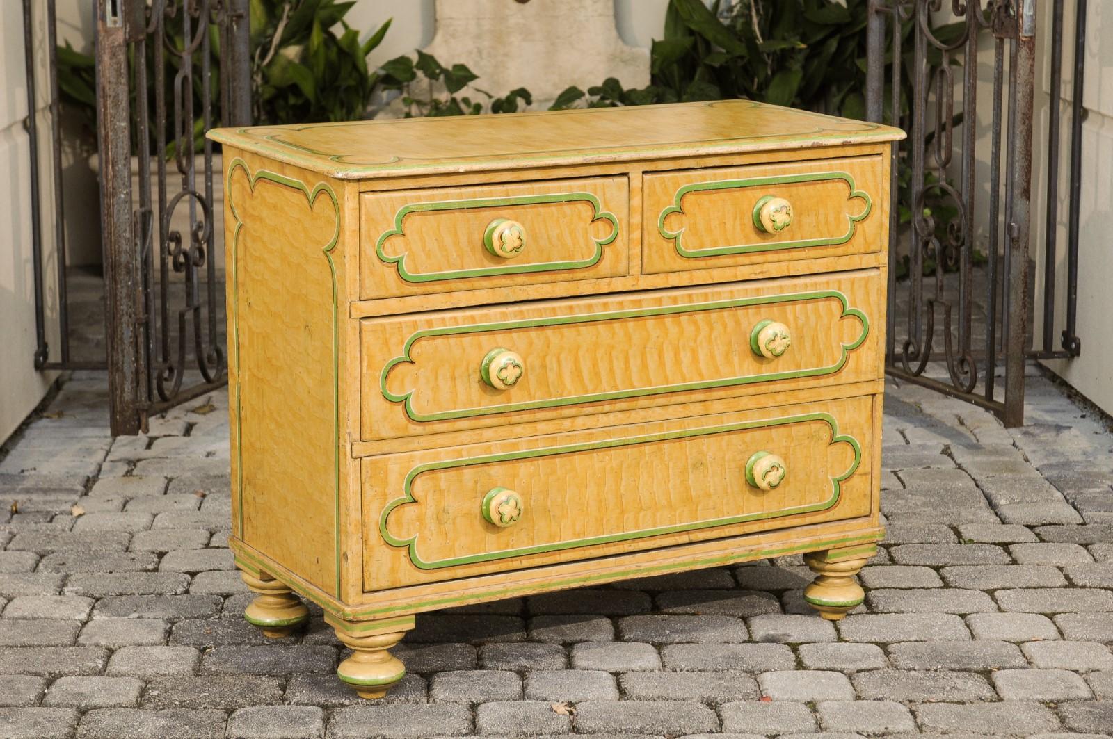 An English painted wood four-drawer chest from the late 19th century, with curvy cartouche motifs and turned feet. Born in England during the last quarter of the 19th century, this chest-of-drawers charms us with its clean lines and painted finish.