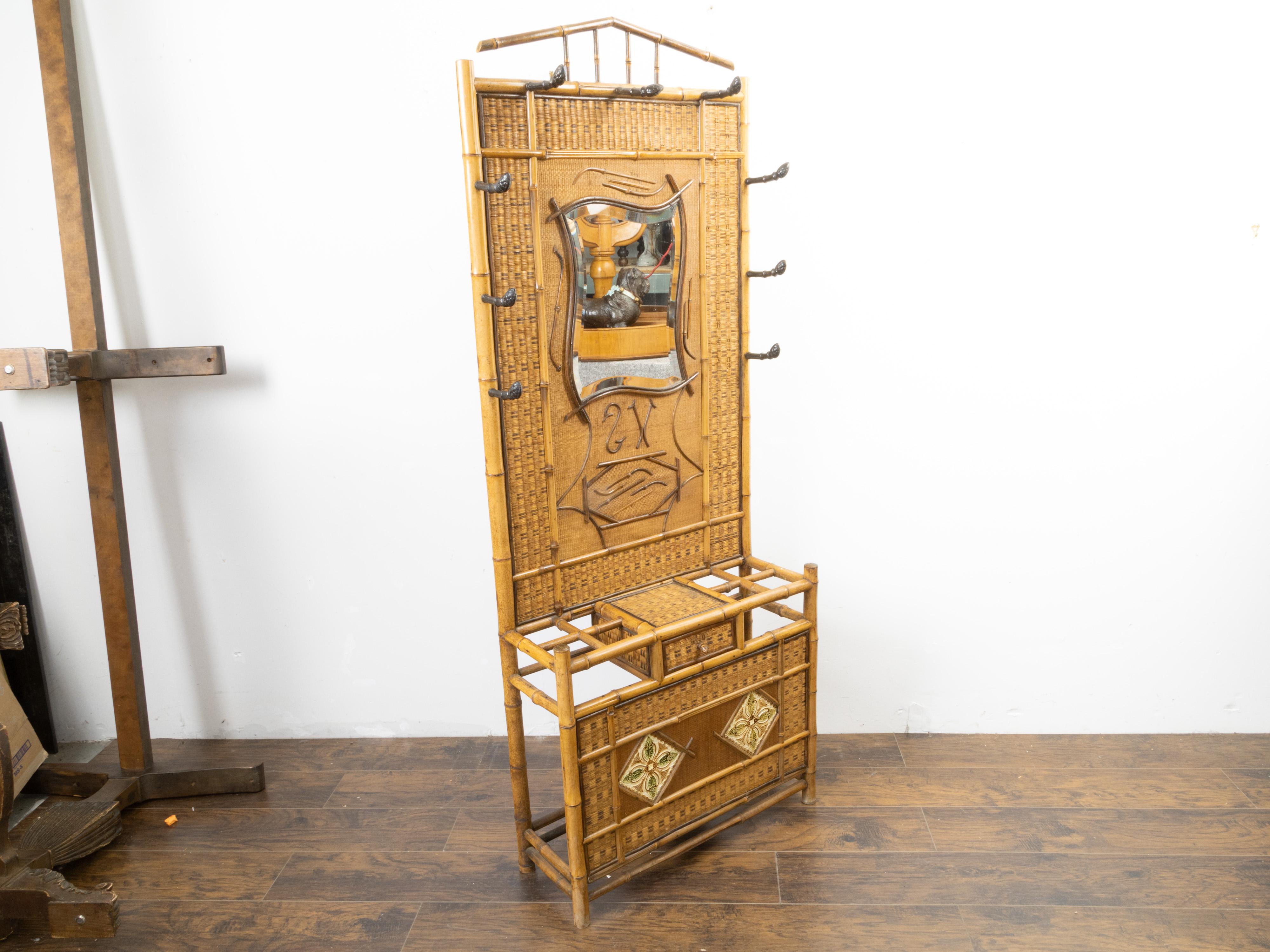 An English bamboo and rattan hat rack from the late 19th century, with mirror and tiles. Created in England during the last quarter of the 19th century, this freestanding hat rack features a bamboo and rattan structure securing a mirror with wavy