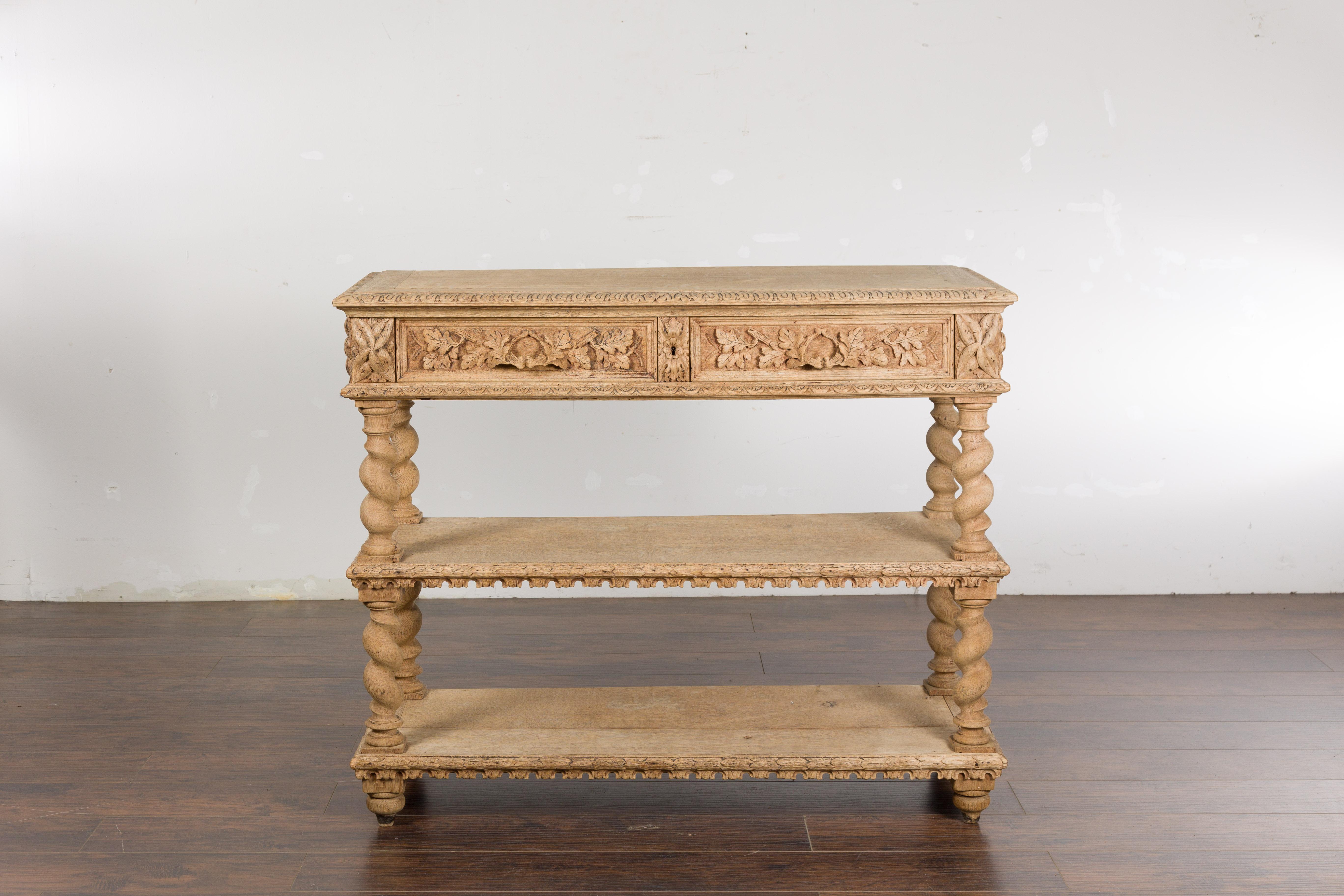 An English oak console table circa 1880 with barley twist base, two foliage carved drawers and two lower shelves. Capture the timeless elegance of English craftsmanship with this stunning oak console table from the late 19th century. Crafted circa