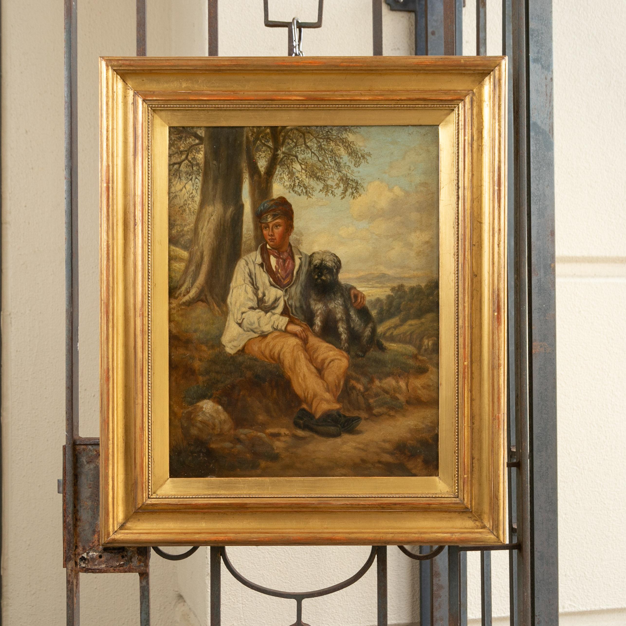 An English oil on canvas painting from the late 19th century depicting a boy sitting with his dog, in antique giltwood frame. Created in England during the last quarter of the 19th century, this oil on canvas painting charms us with its heartwarming