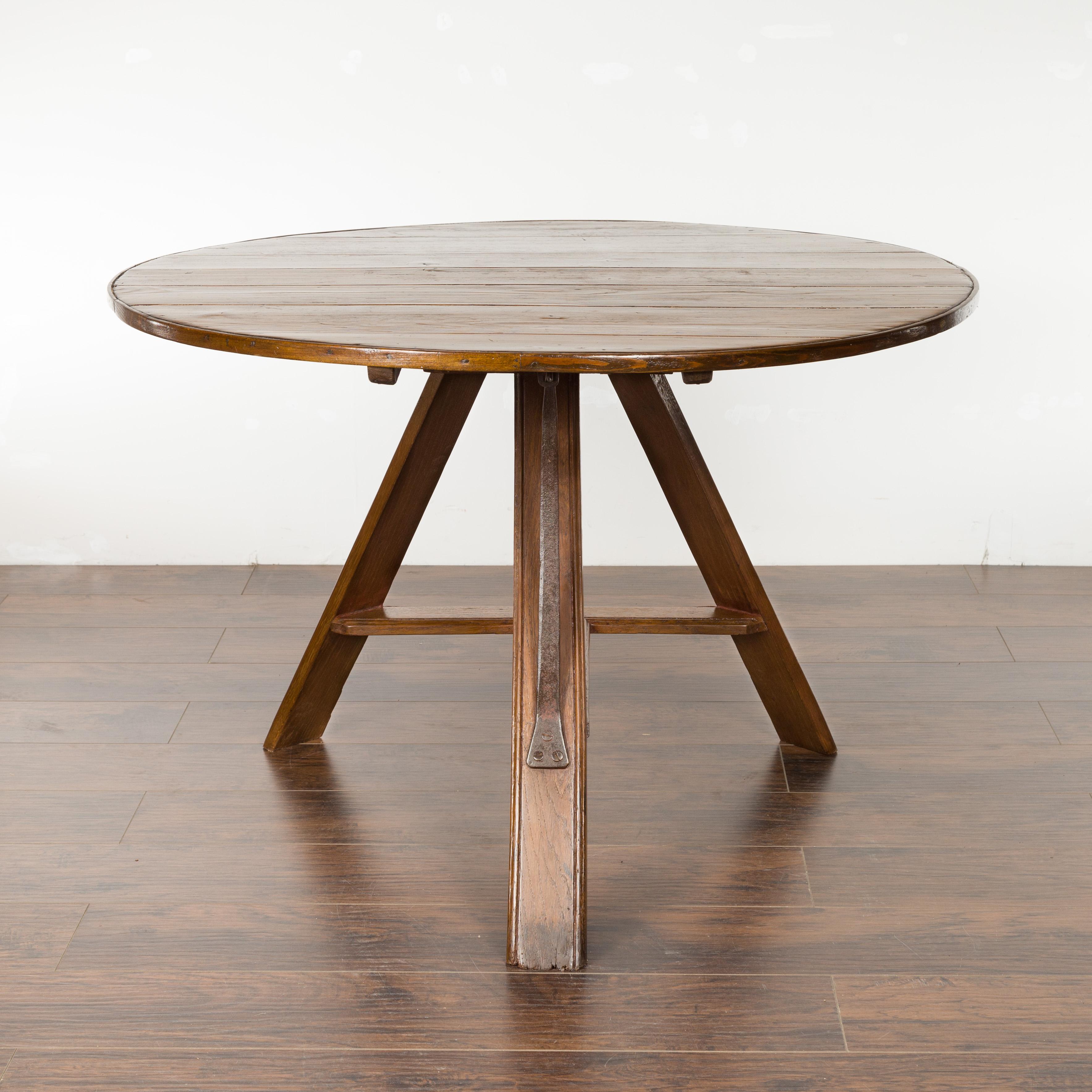 An English pine round tilt-top wine tasting table from the late 19th century, with metal strap. Created in England during the last quarter of the 19th century, this pine table features a circular tilt top resting above a tripod base made of three