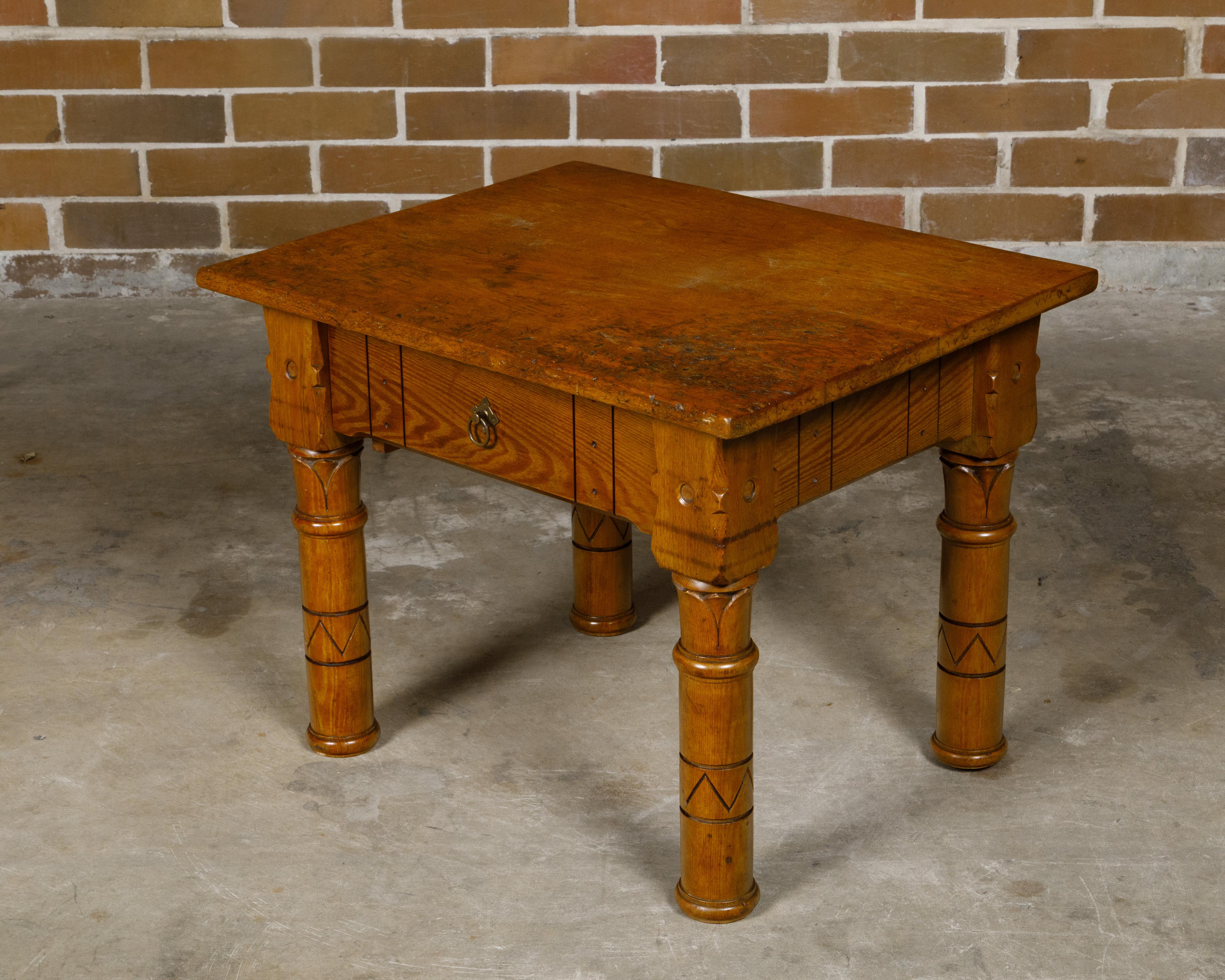 An English pine coffee table from circa 1880 with single drawer and lotiform style column legs. Born in England circa 1880, this charming pine coffee table embodies the rustic elegance and craftsmanship of the late 19th century. The table features a