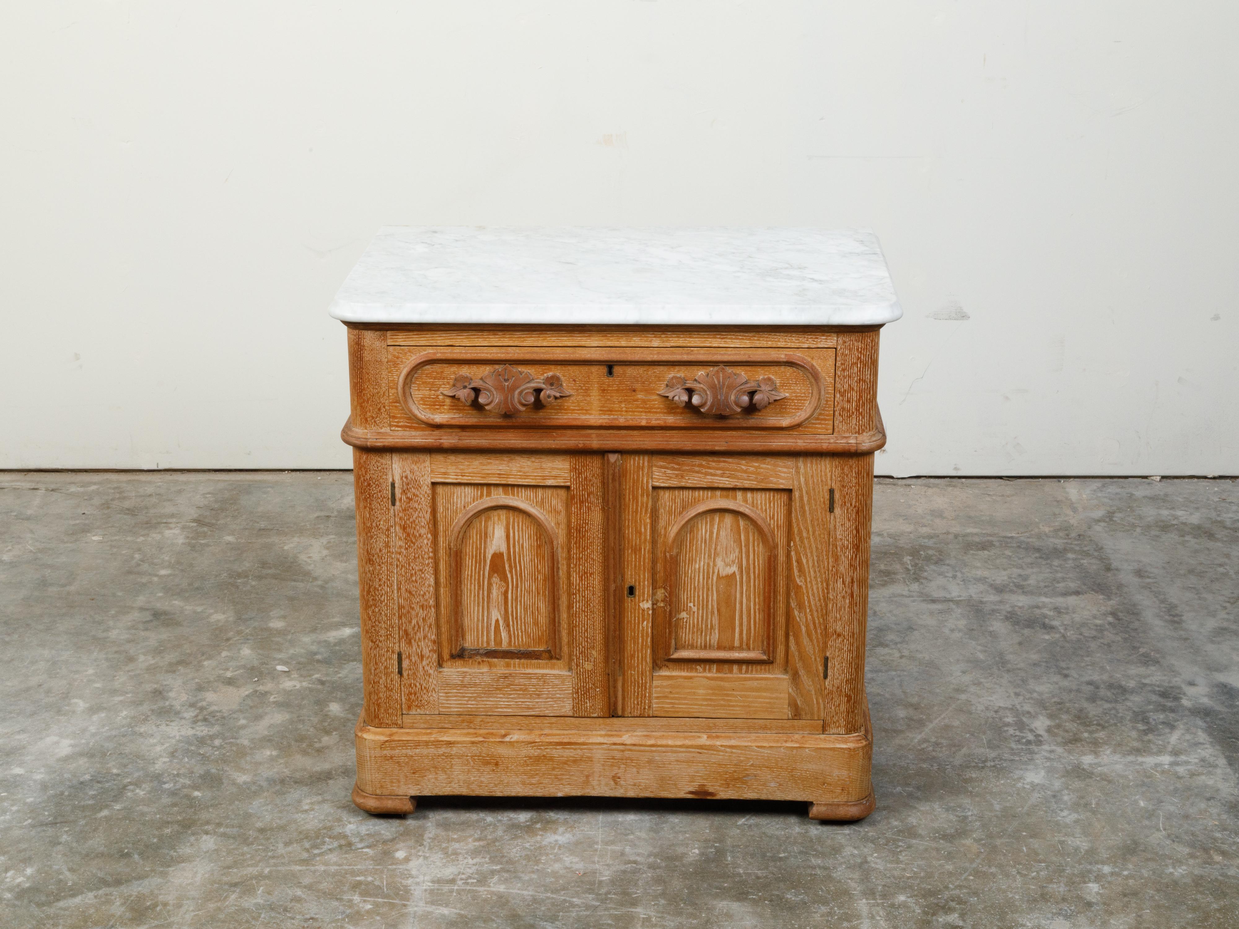 An English pine or chestnut small cabinet from the late 19th century, with white marble top, carved drawer and two doors. Created in England during the last quarter of the 19th century, this small cabinet features a rectangular white marble top with