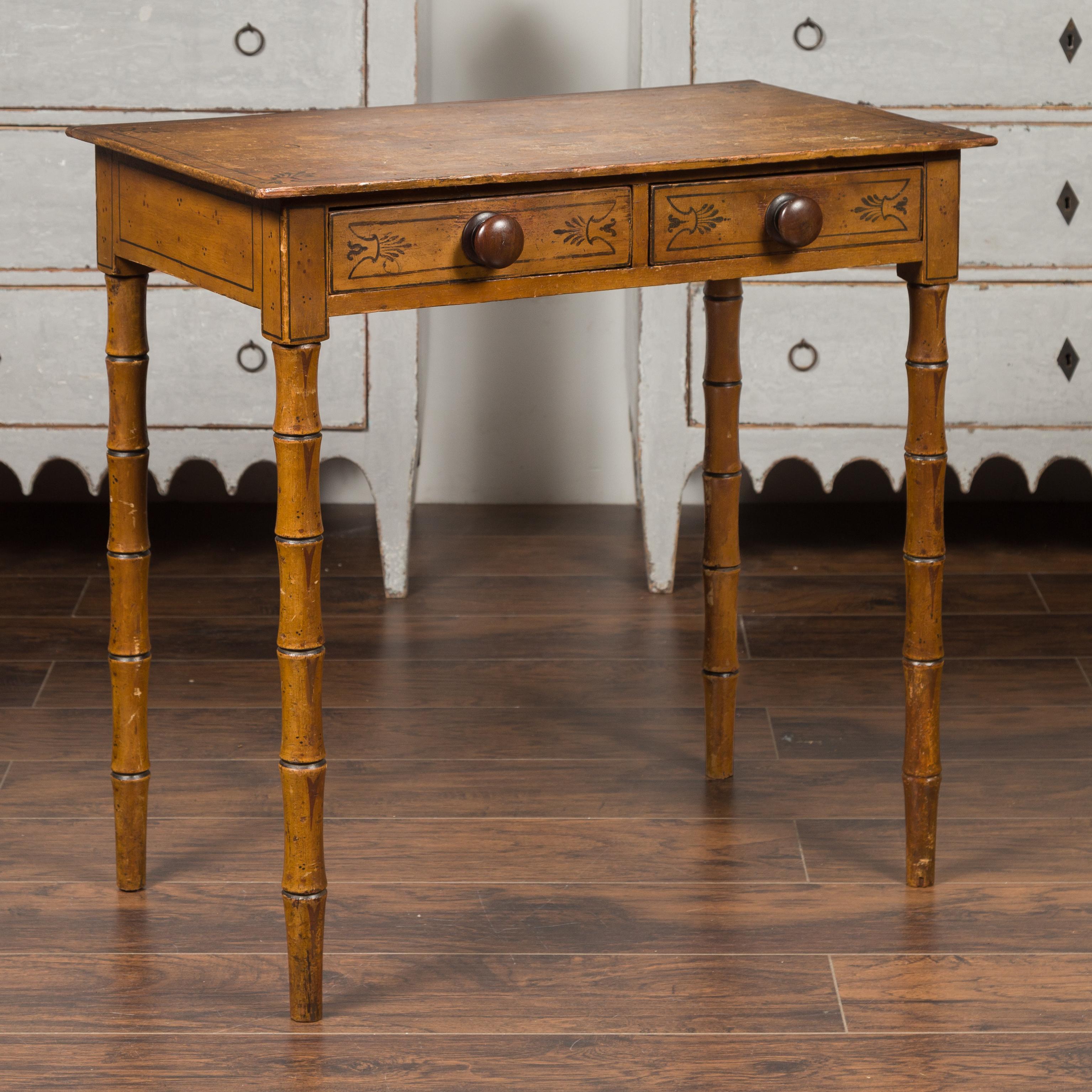 An English painted table from the late 19th century, with two drawers and faux bamboo legs. Born in England during the later years of the 19th century, this table features a rectangular top with distressed appearance, sitting above two drawers each