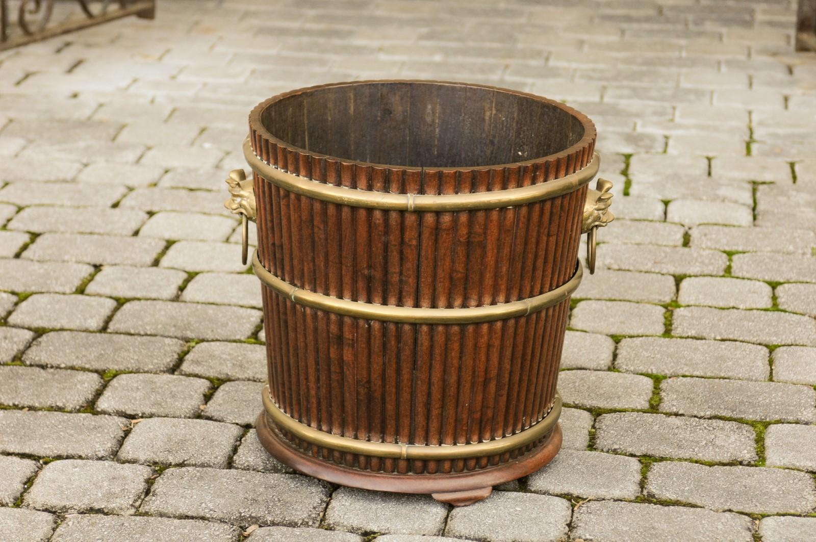 An English wooden bucket from the late 19th century, with reeded accents and brass motifs. Born in England during the later years of the 19th century, this charming bucket will charm you with its versatile aspect. Whether used as a planter, cachepot