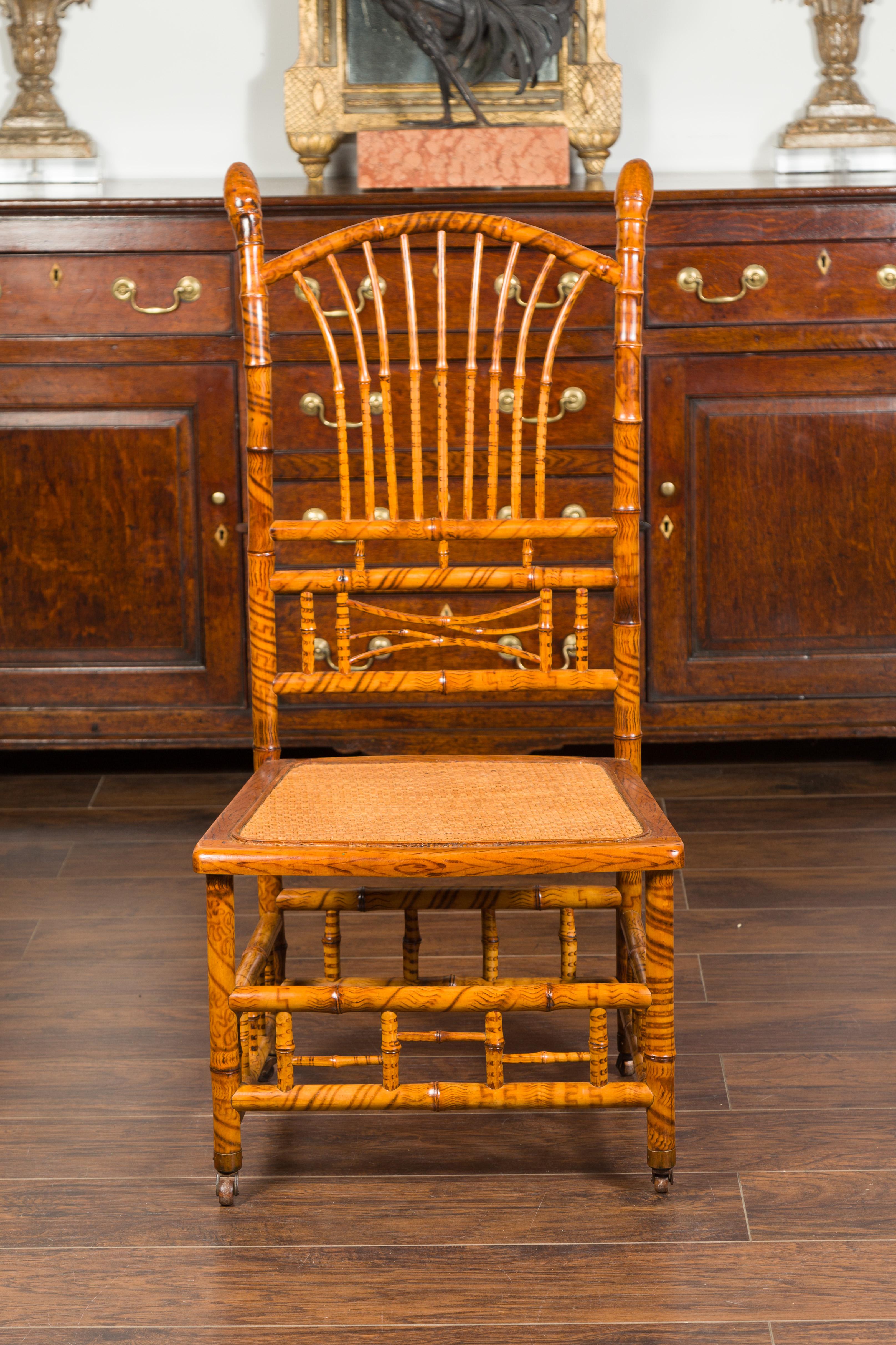 An English bamboo slipper chair from the late 19th century, with fan back, woven rattan seat and casters. Created in England during the last decade of the 19th century, this bamboo slipper chair features a slightly out-curving back adorned with fan