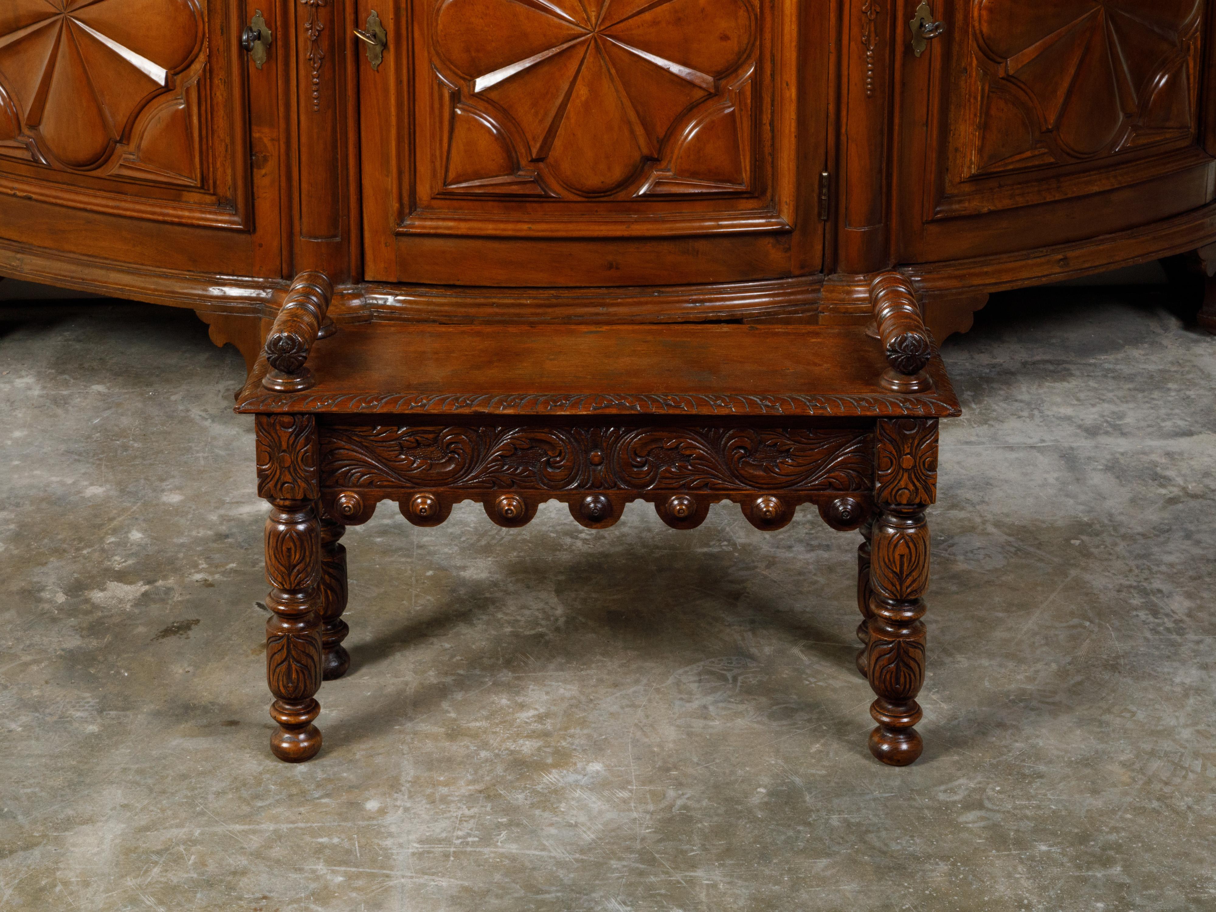 An English oak bench from the late 19th century, with carved foliage and cylindrical armrests. Created in England during the last quarter of the 19th century, this oak hall bench features a rectangular seat with carved edges, accented with two