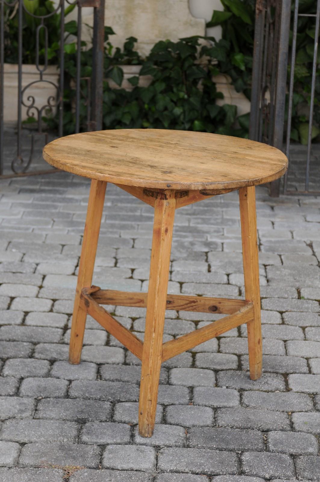 An English rustic pine cricket table from the late 19th century, with circular top and triangular side stretcher. Born during the last quarter of the 19th century, this rustic cricket side table features a circular top, sitting above a simple